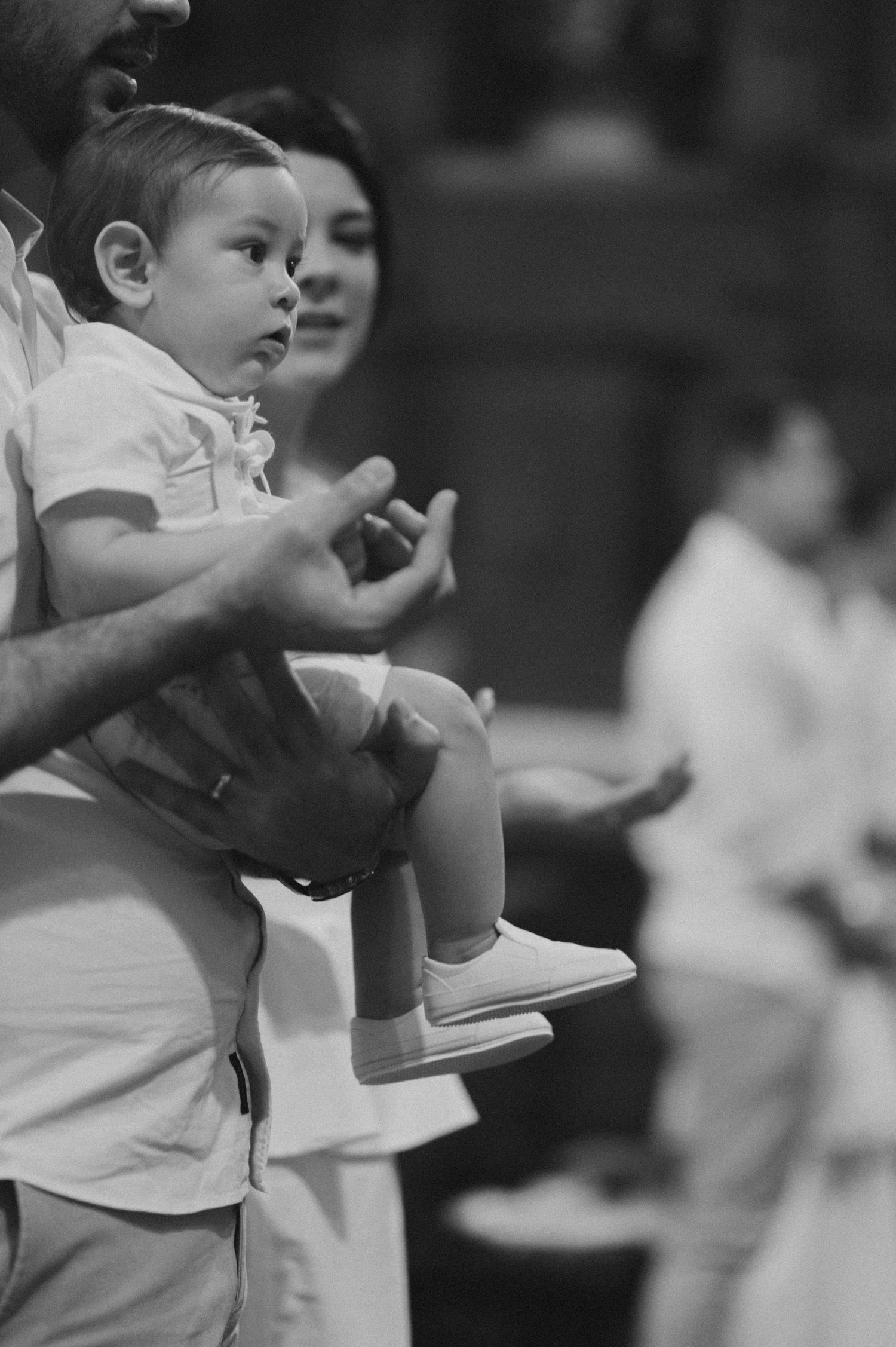 Children in white clothing participating in a church ceremony with raised hands.