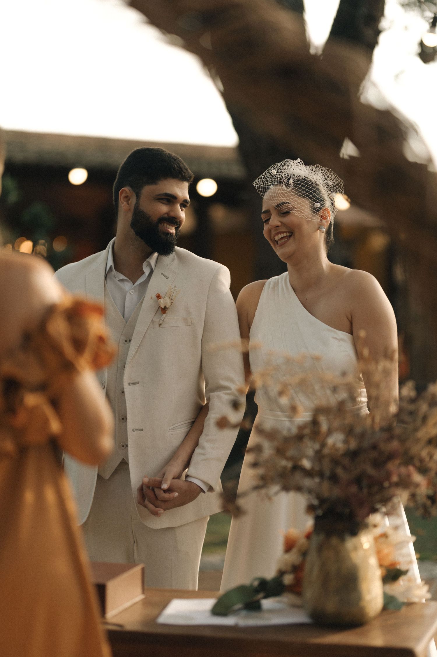 A couple shares a joyful moment together at their wedding reception while cutting their wedding cake.