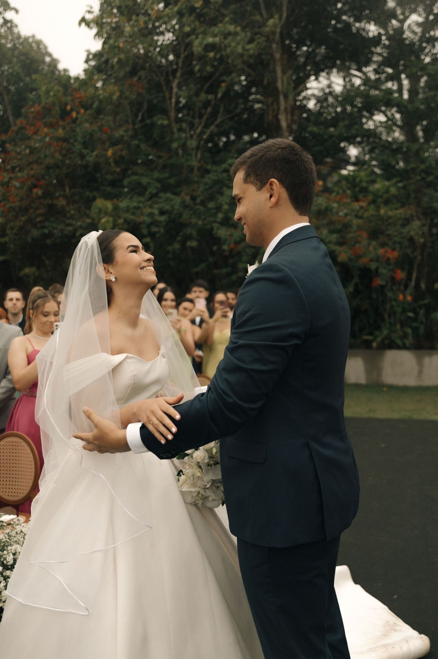 A joyful couple shares their first dance at a wedding reception outdoors surrounded by guests.