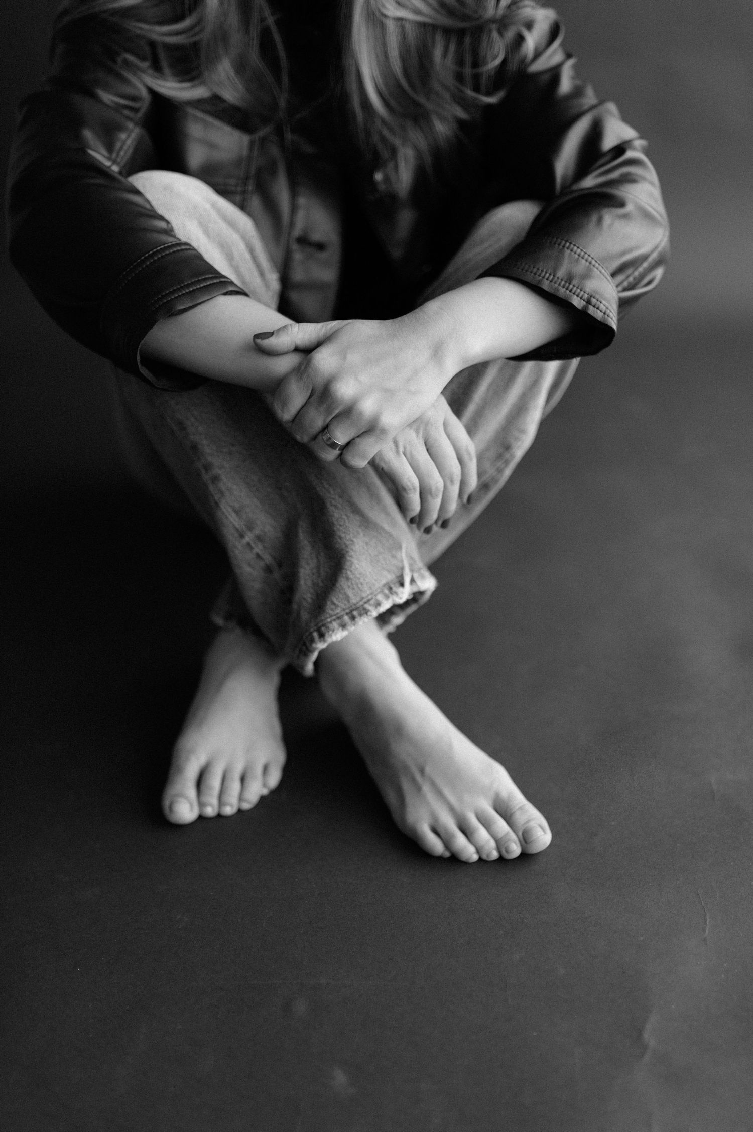 Black and white photo of crossed legs and bare feet in casual denim.