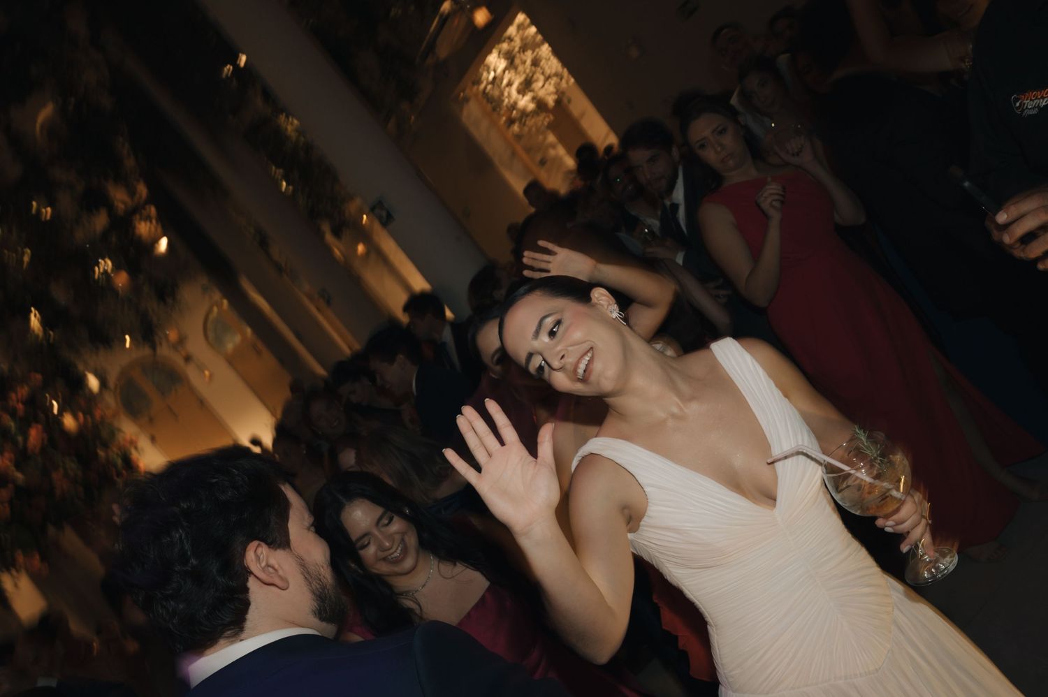 Wedding reception guests dancing and celebrating on a dimly lit dance floor at an evening party.