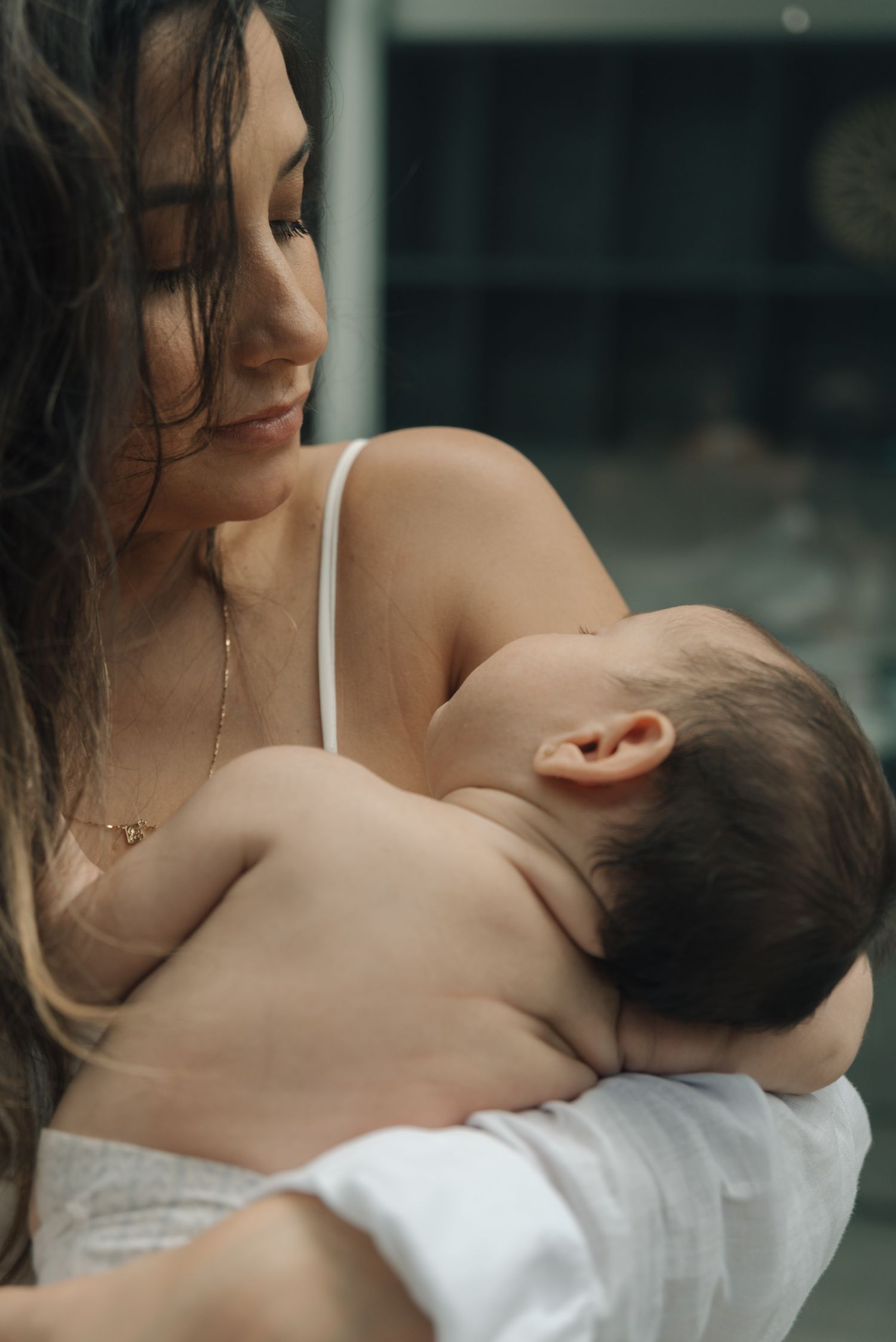 An intimate nurturing moment captured in natural light with parent cradling baby.