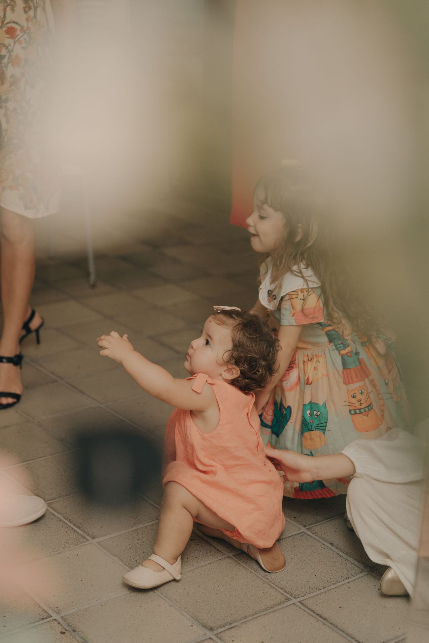 Children sitting on tiled floor reaching for something during a party.