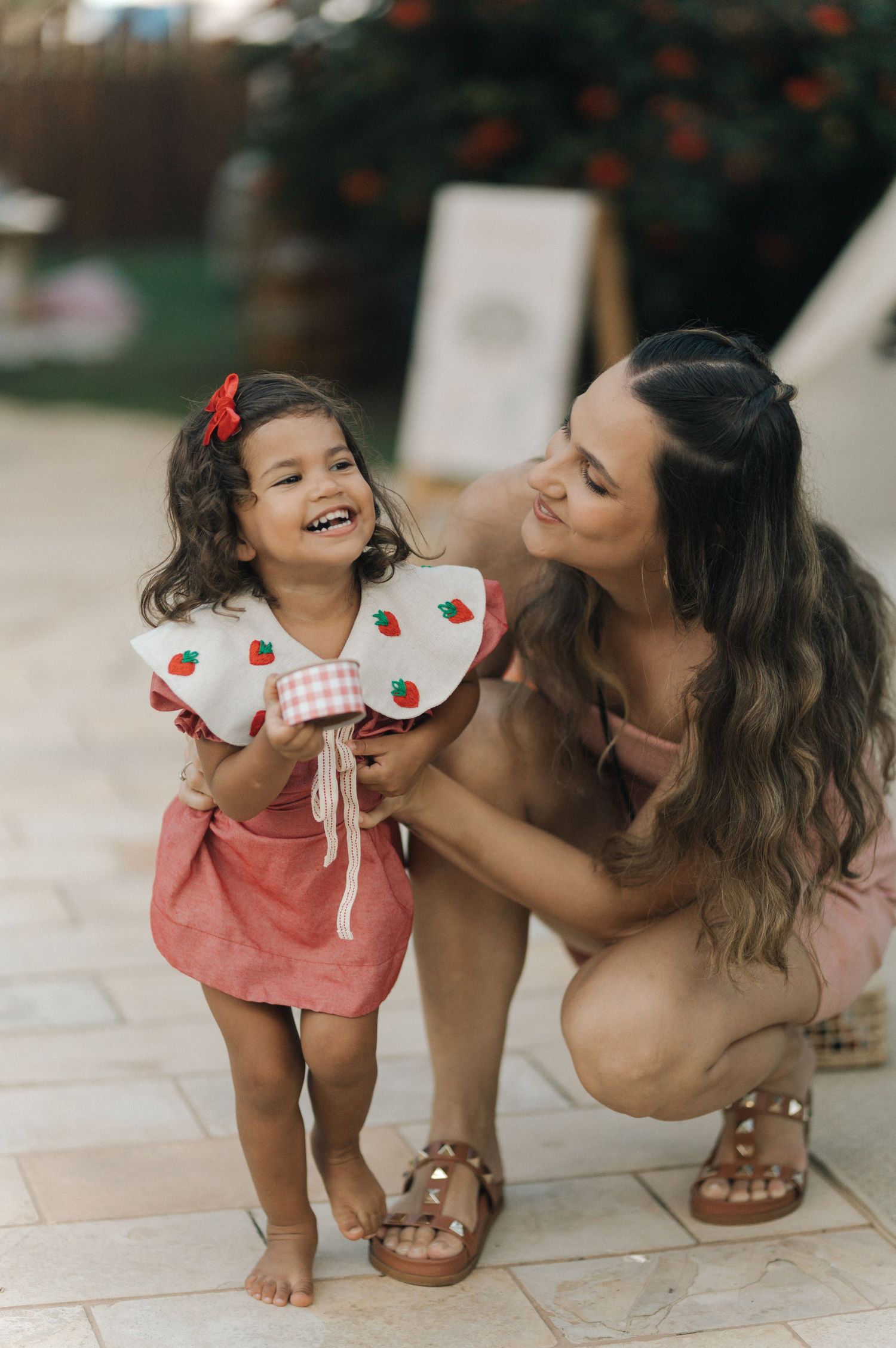 A tender moment captured outdoors showing joyful interaction in coordinated pink outfits on a tiled patio.