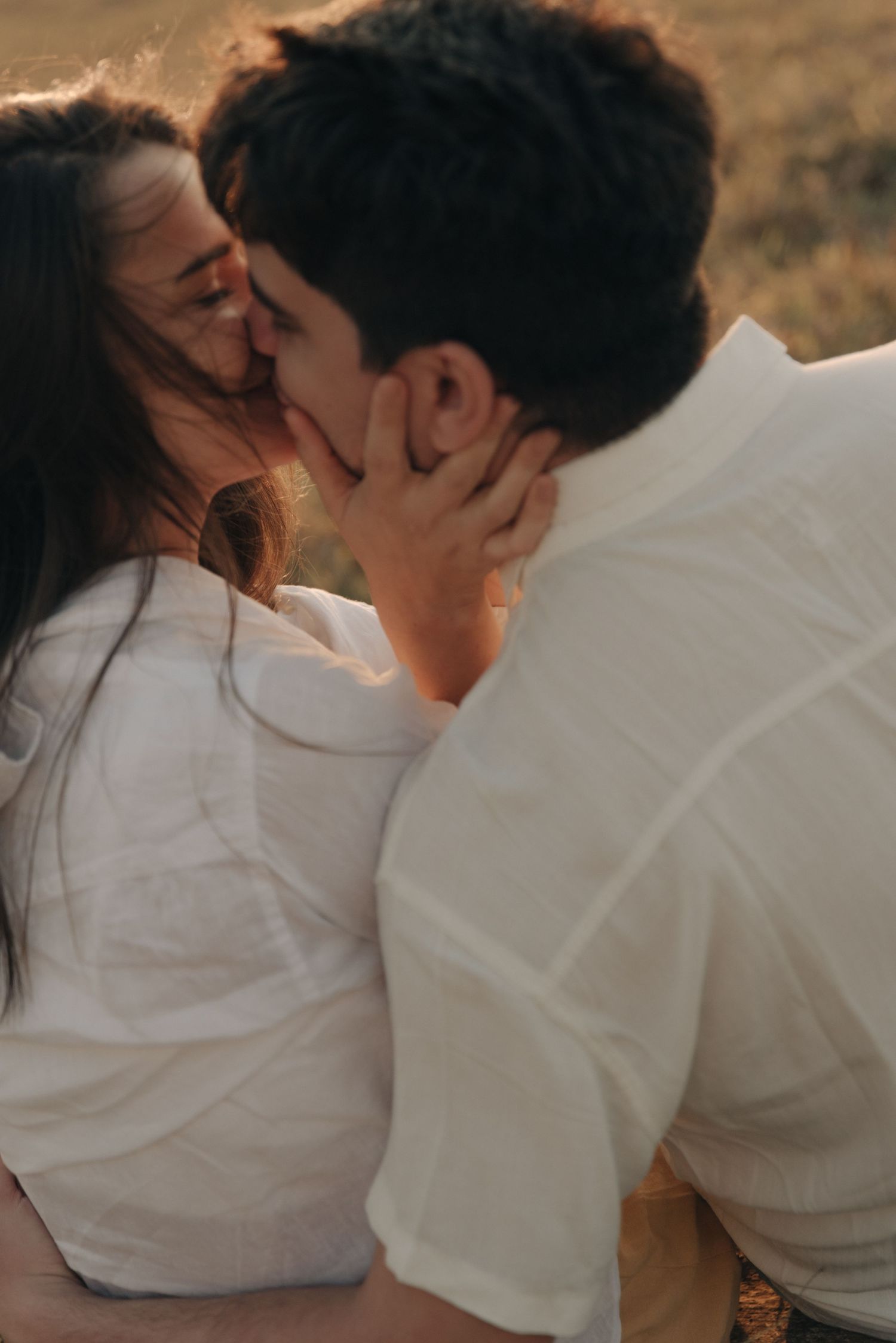 An intimate close-up of a couple sharing a passionate kiss outdoors.