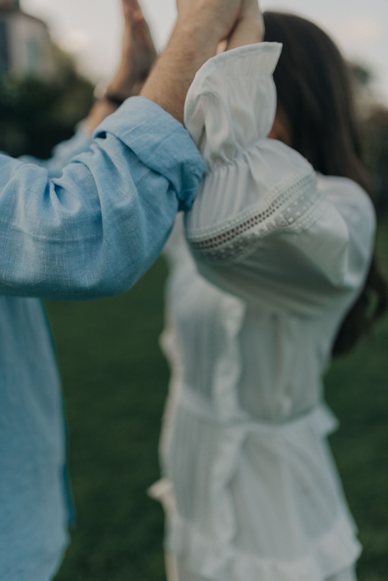 Artistic close-up of couple in blue and white clothing embracing outdoors.