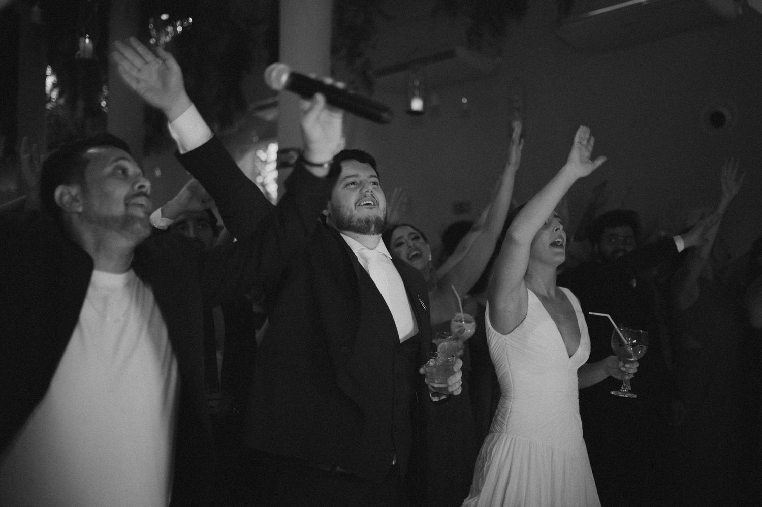 People dancing and celebrating at a dark nightclub or party venue with atmospheric lighting.