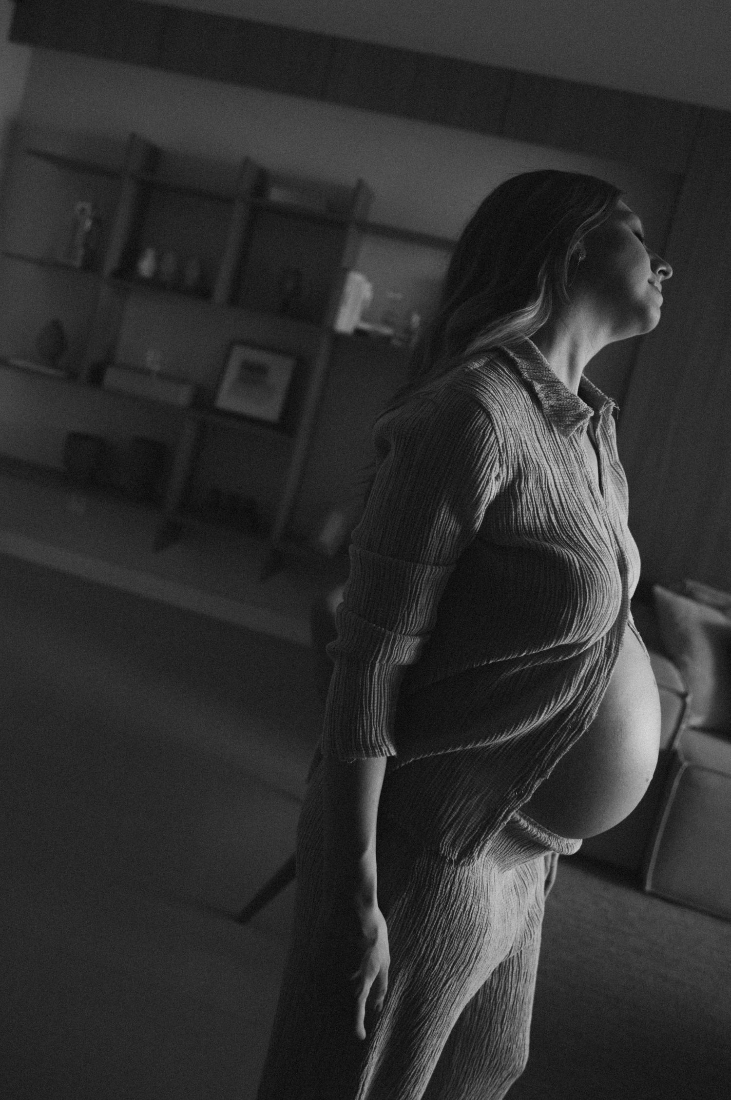 Artistic black and white maternity photo showcases silhouette in fitted dress.