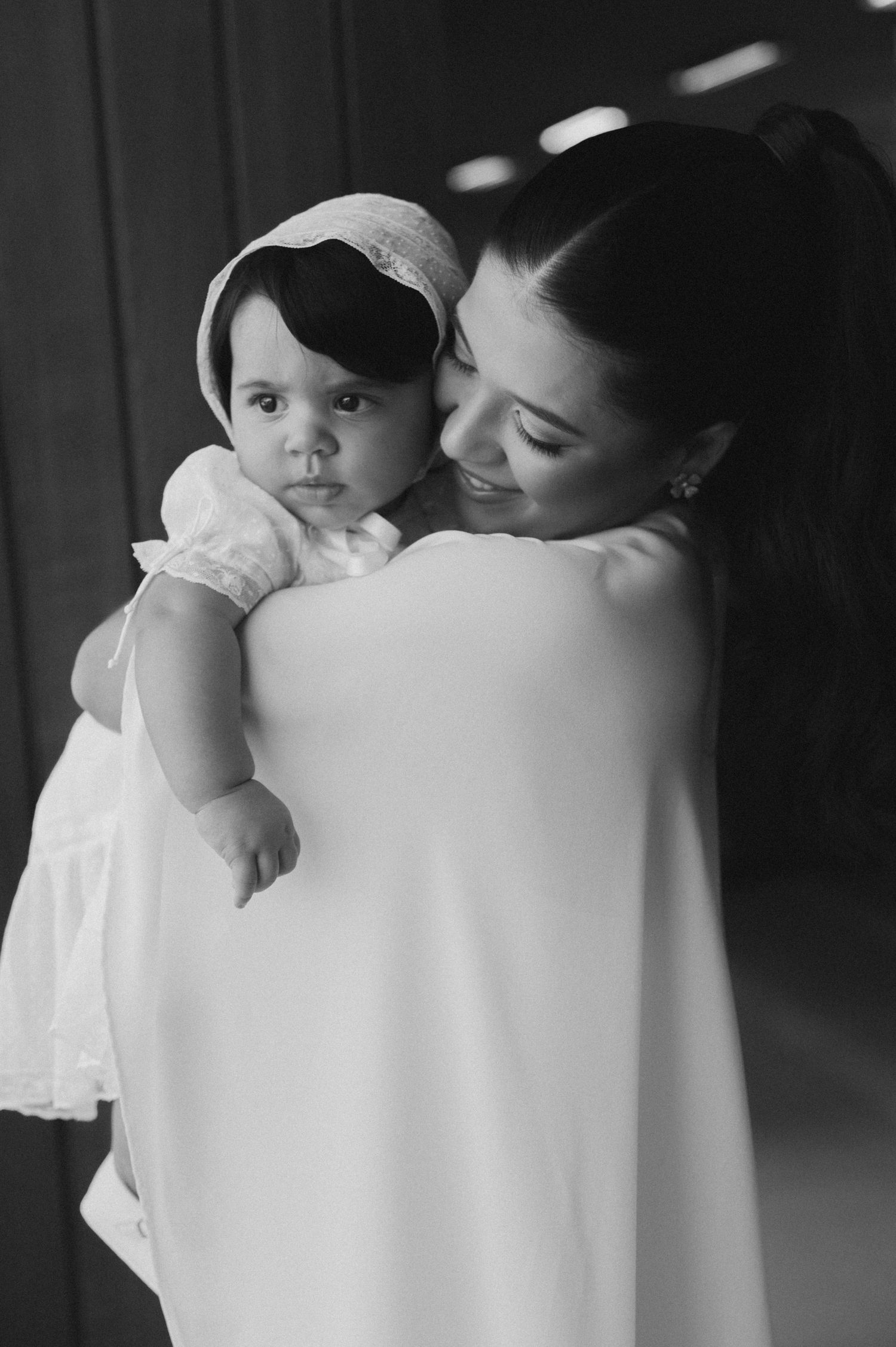 Black and white photo series showing tender moments between parent and baby in white clothing.
