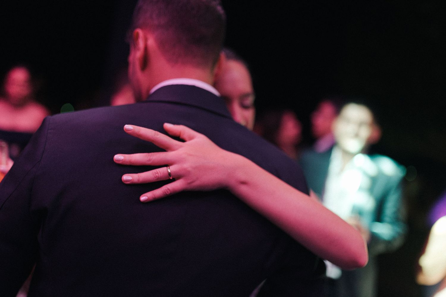 Couple sharing an intimate dance embrace at a formal event, woman's hand resting on man's shoulder.
