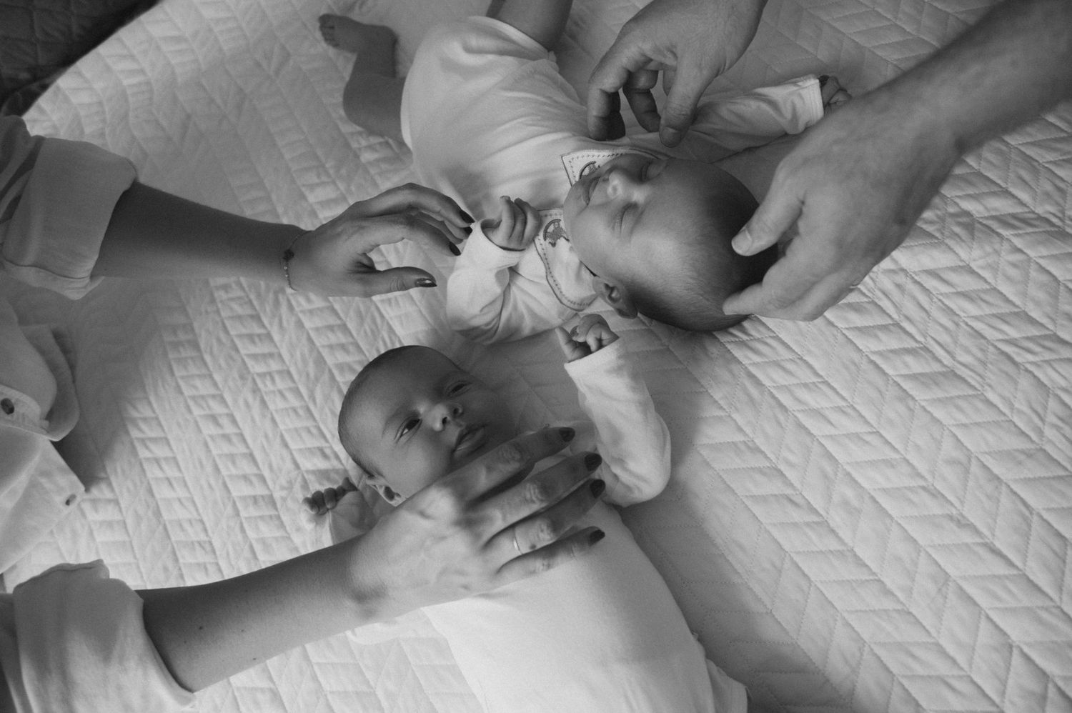 Black and white photo series showing a baby lying on a blanket with hands reaching in to comfort and care for them.