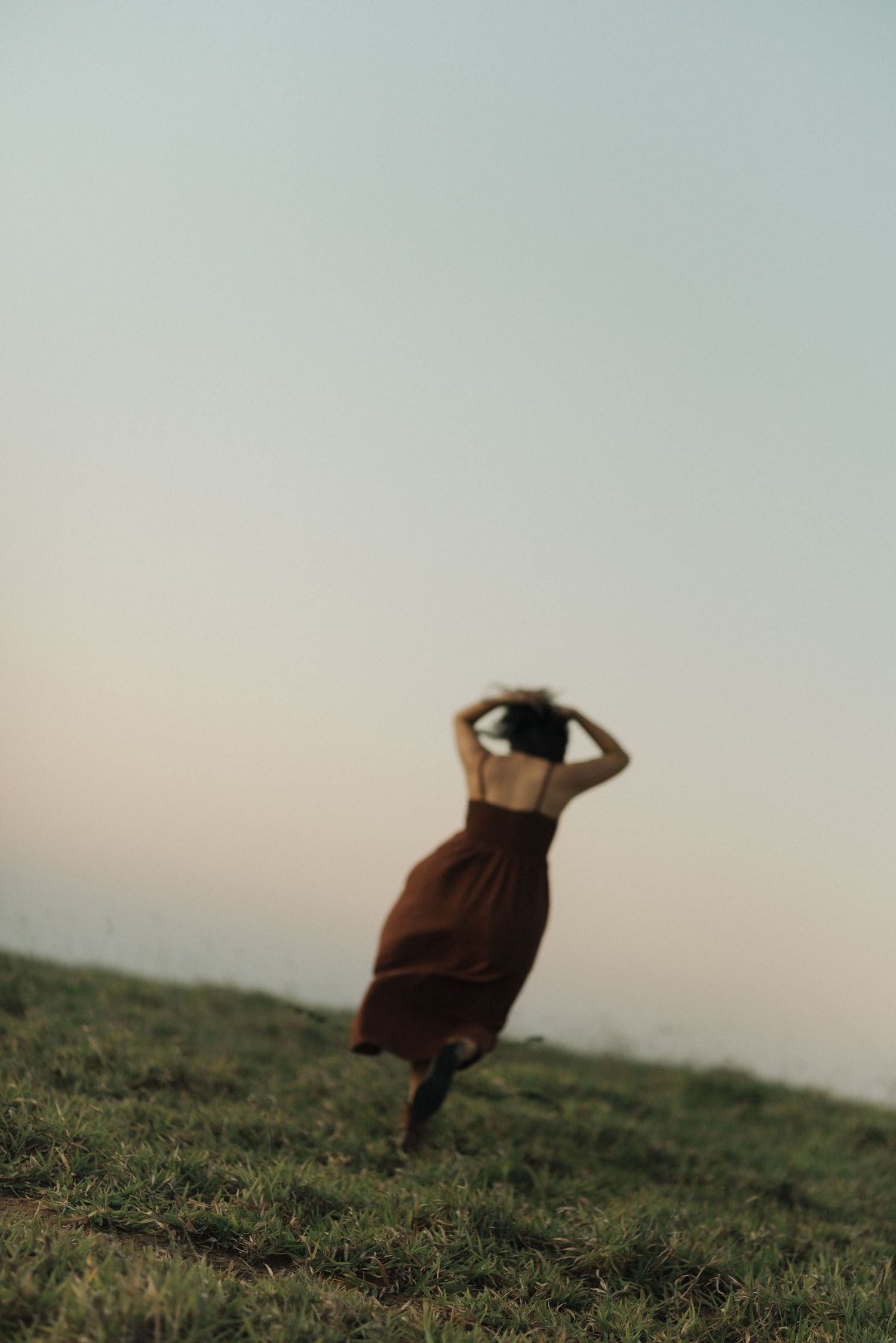 Artistic silhouette of a person in motion on a hilltop during golden hour.
