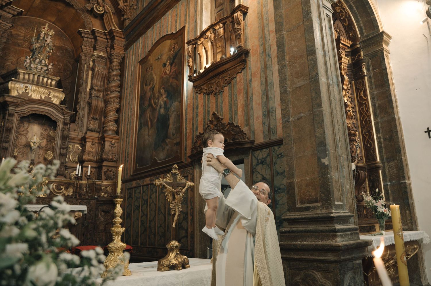 Interior of an ornate baroque church with gilded altars and architectural details illuminated in warm light.
