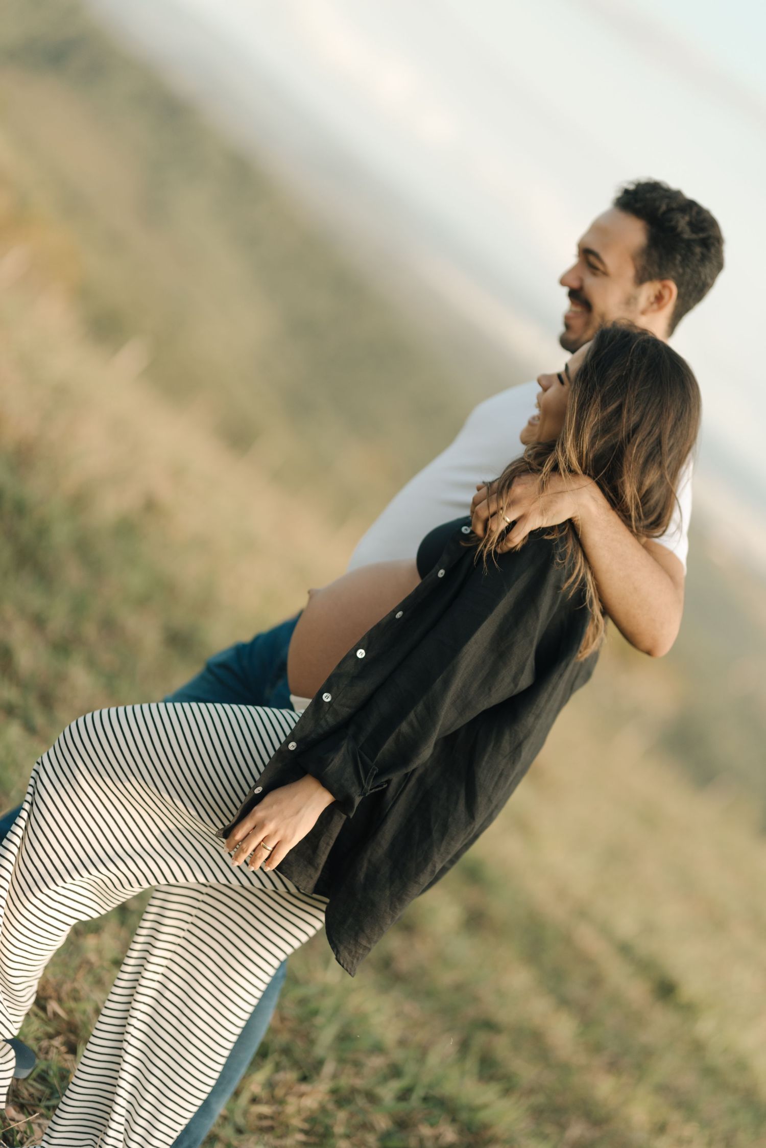 Couple sharing an intimate embrace against a mountainous backdrop.