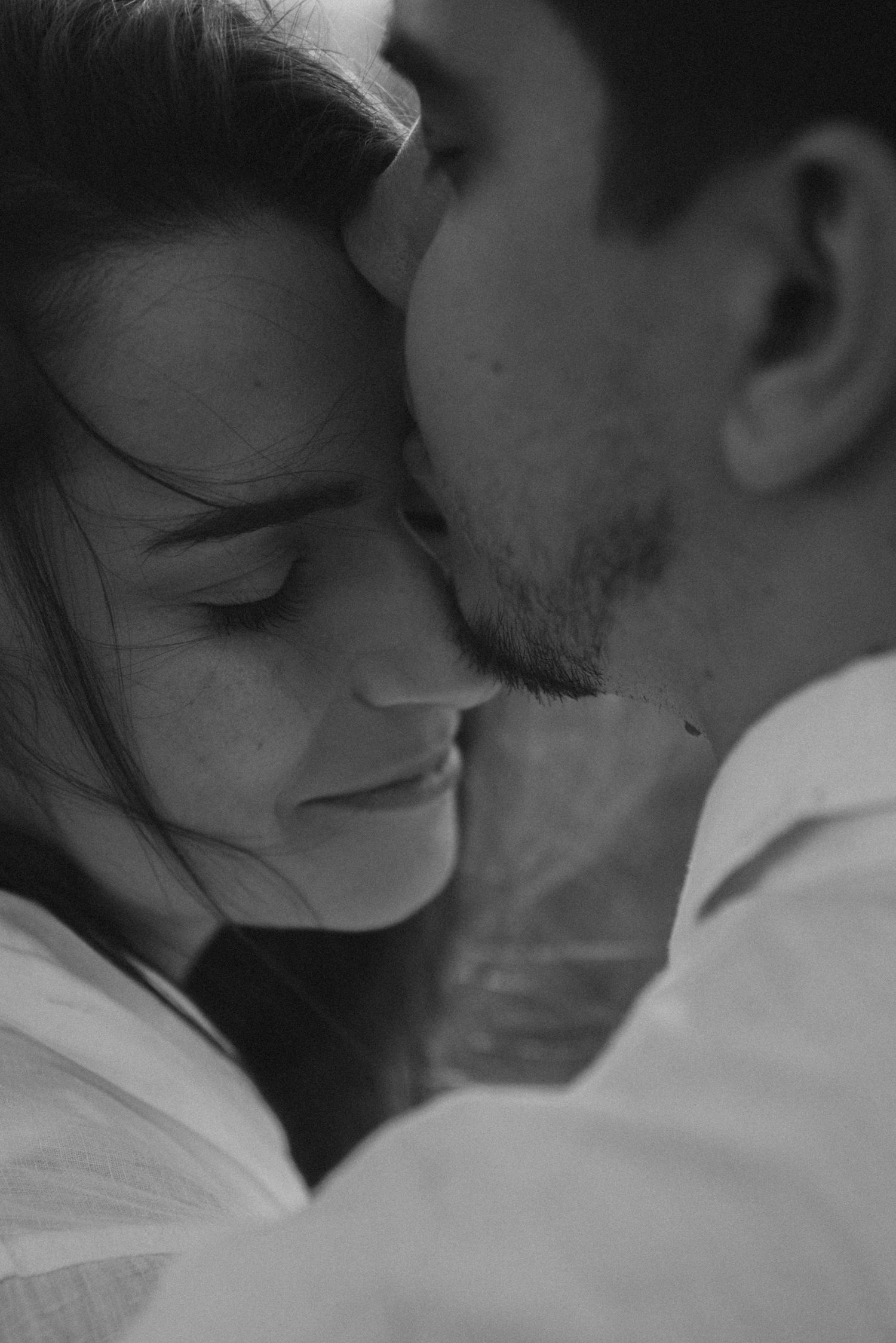 Intimate black and white close-up portrait showing tender romantic moment between couple.