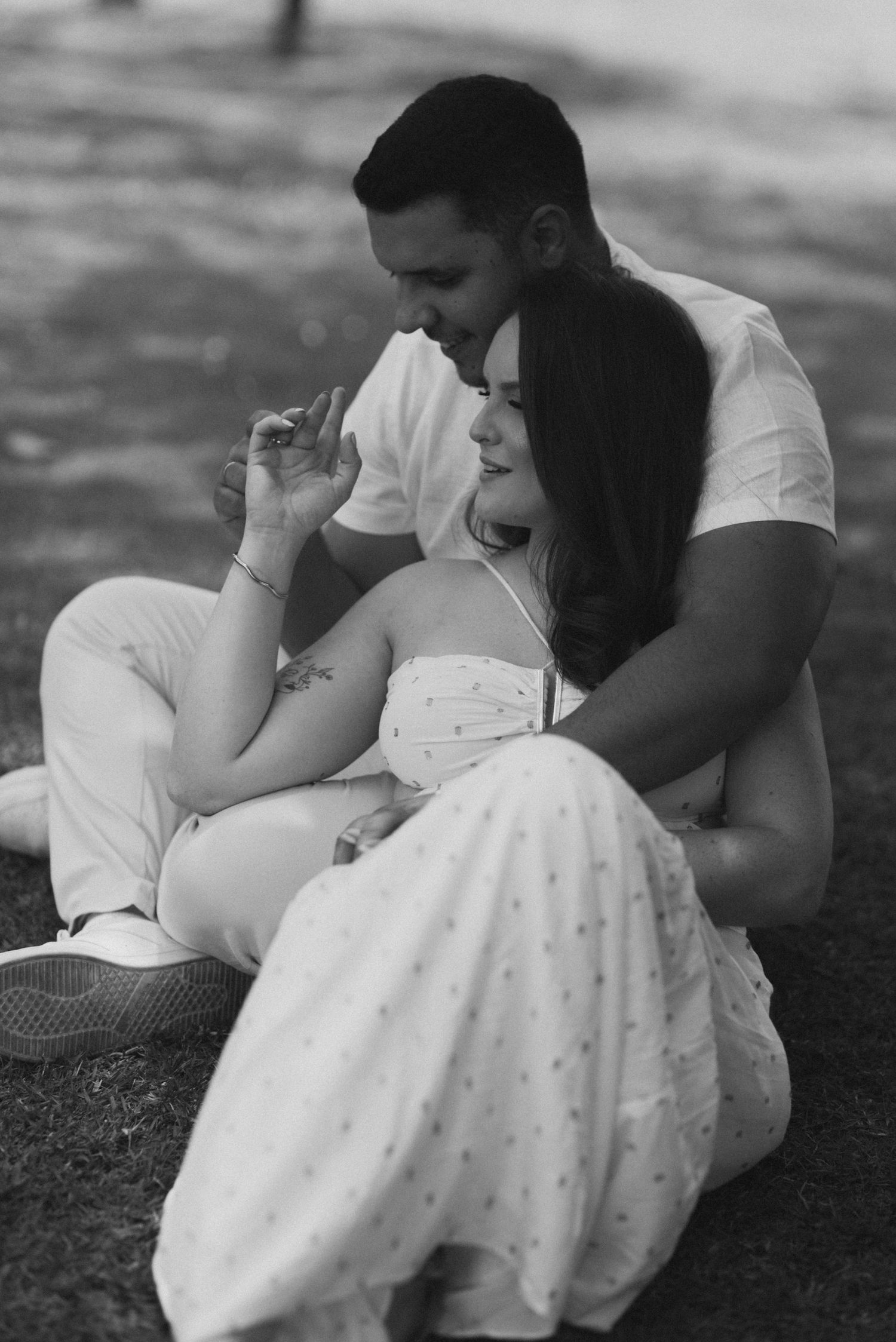 A couple in white outfits relaxing together outdoors in black and white.