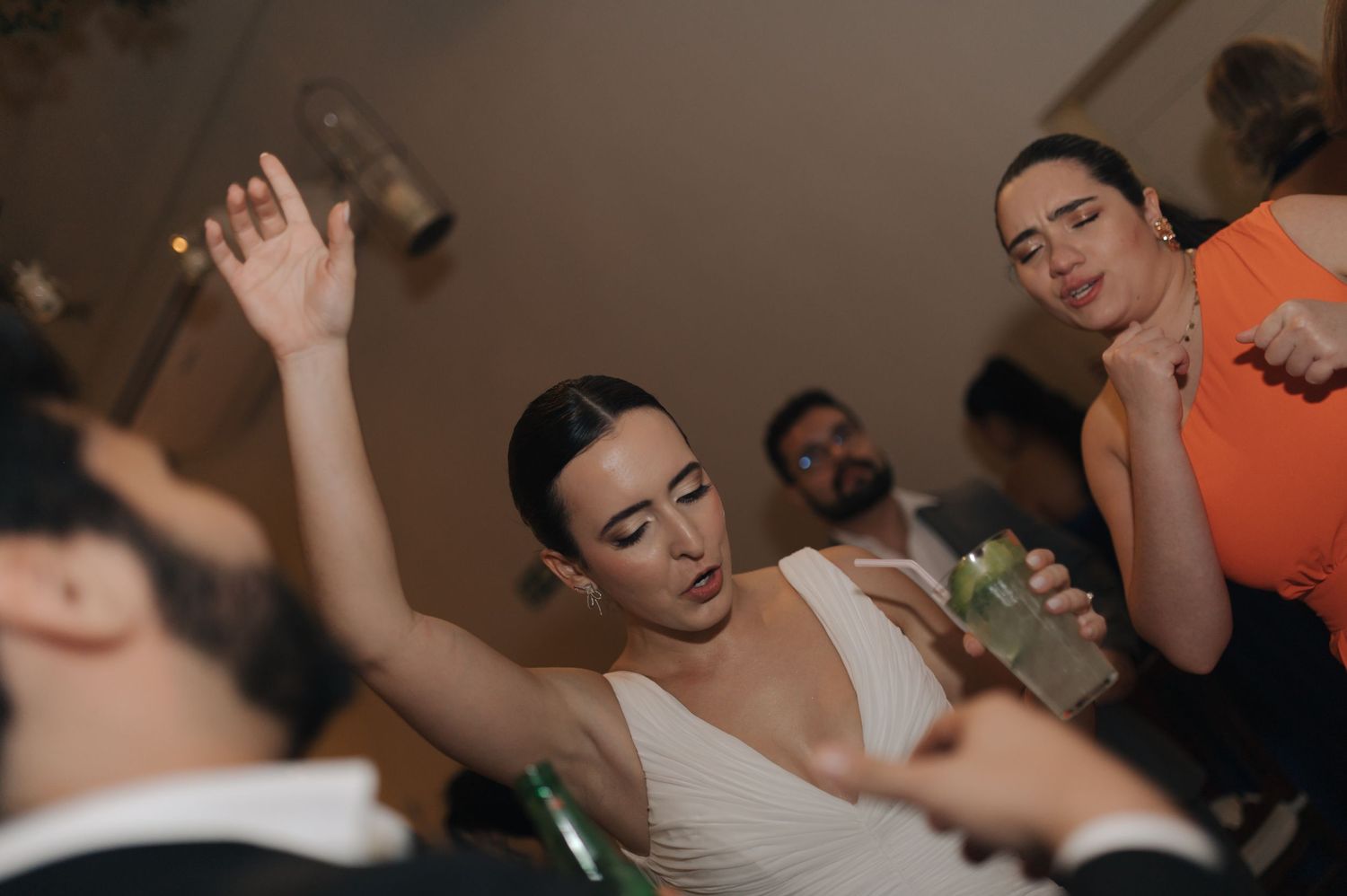A group of people dancing and celebrating together at a party with their arms raised.