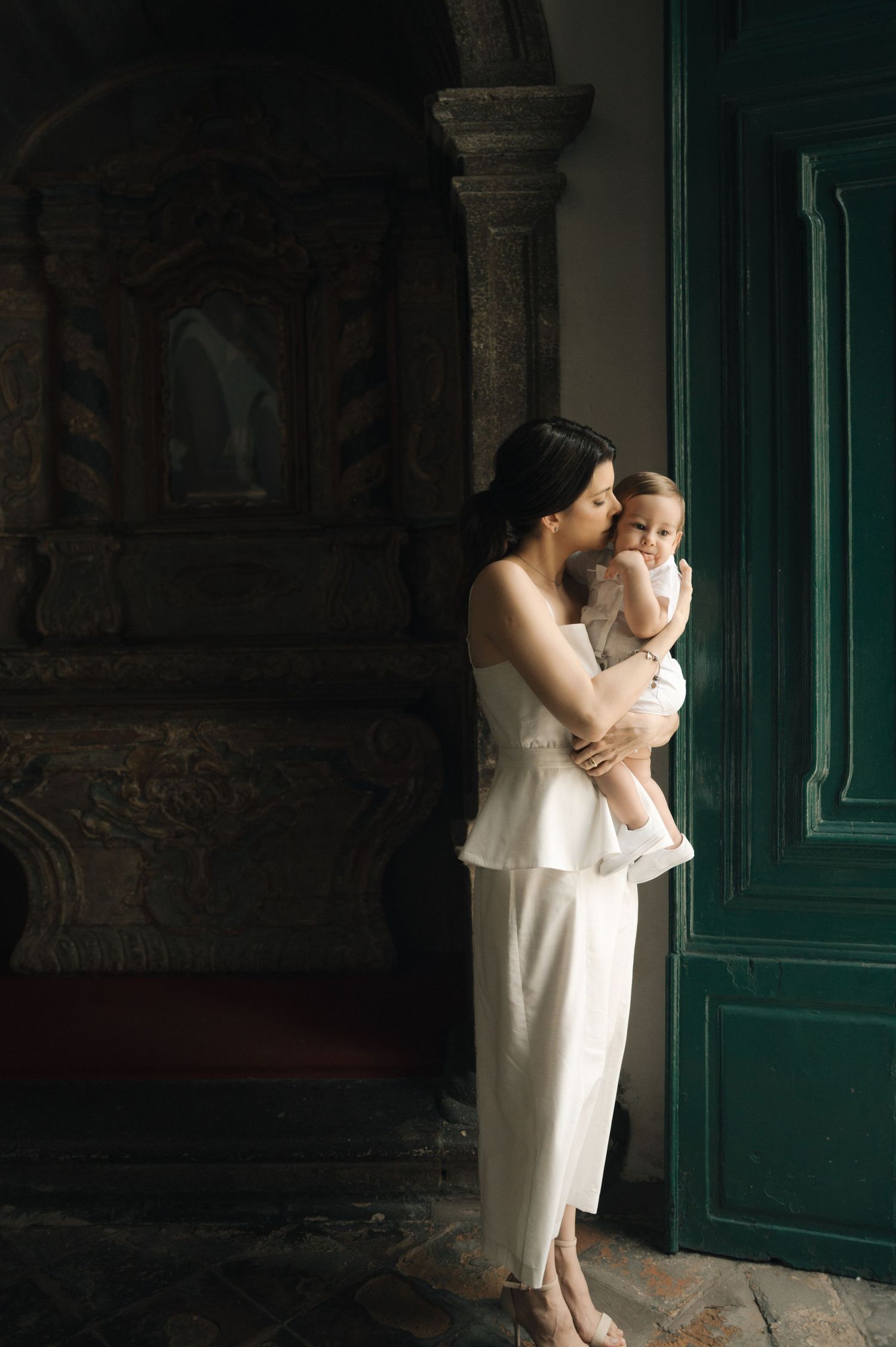 A series of intimate black and white photos showing tender moments between parent and child against a dark green door.