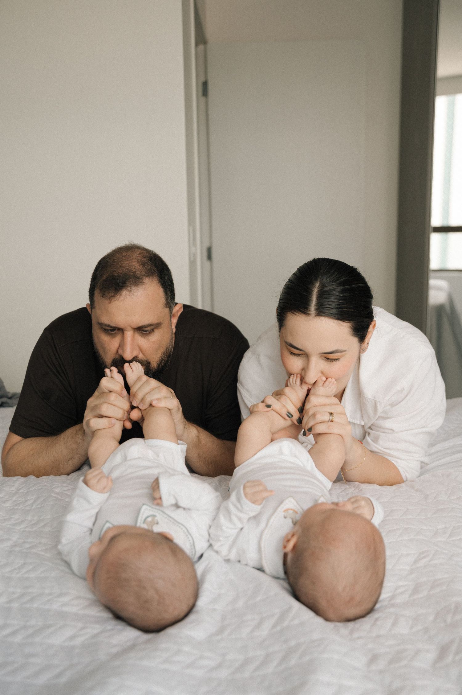 A sequence of three photos showing adults laying on a white bed playing peek-a-boo with a baby.