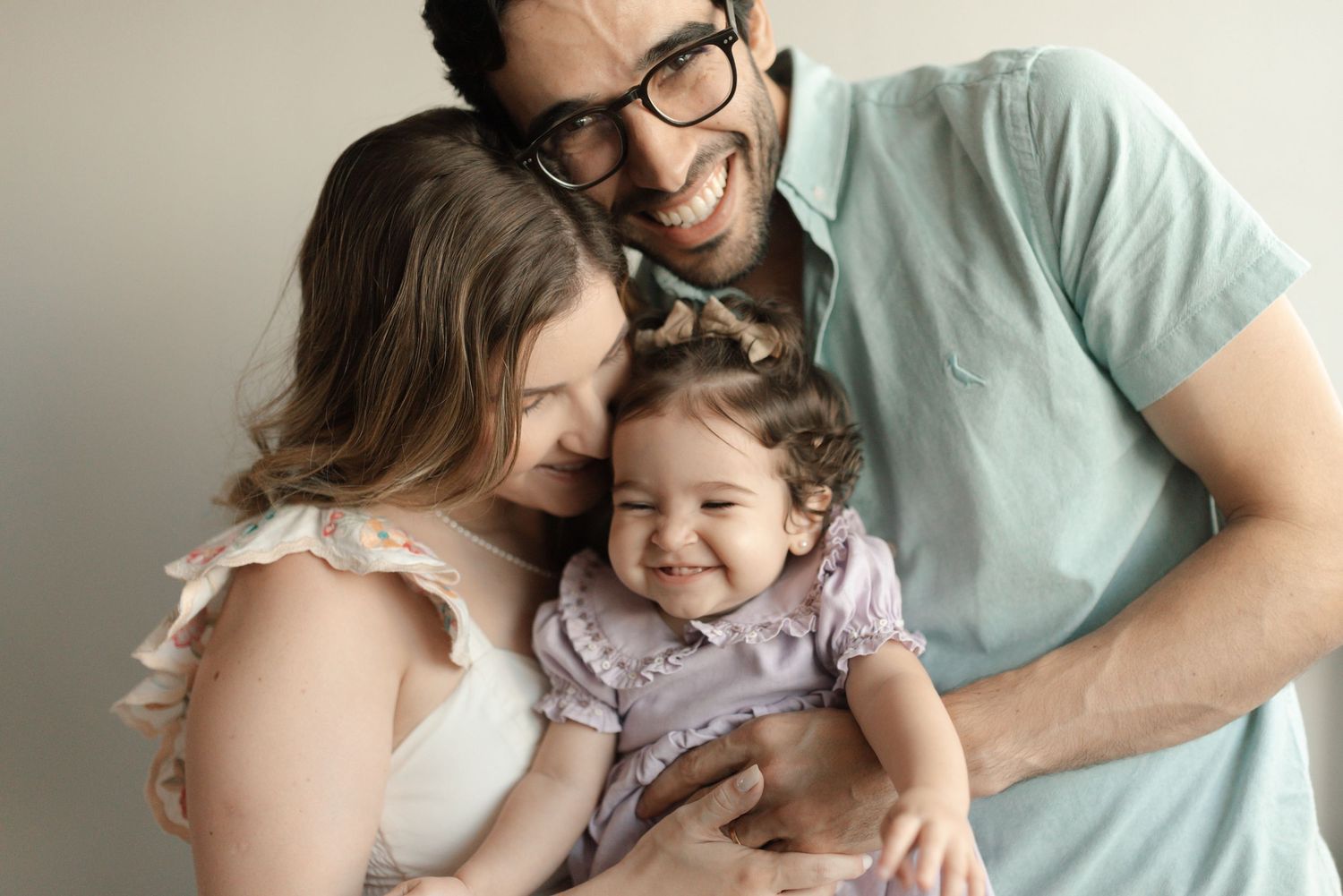 A family shares tender moments and laughter together during an intimate photo session in soft natural light.