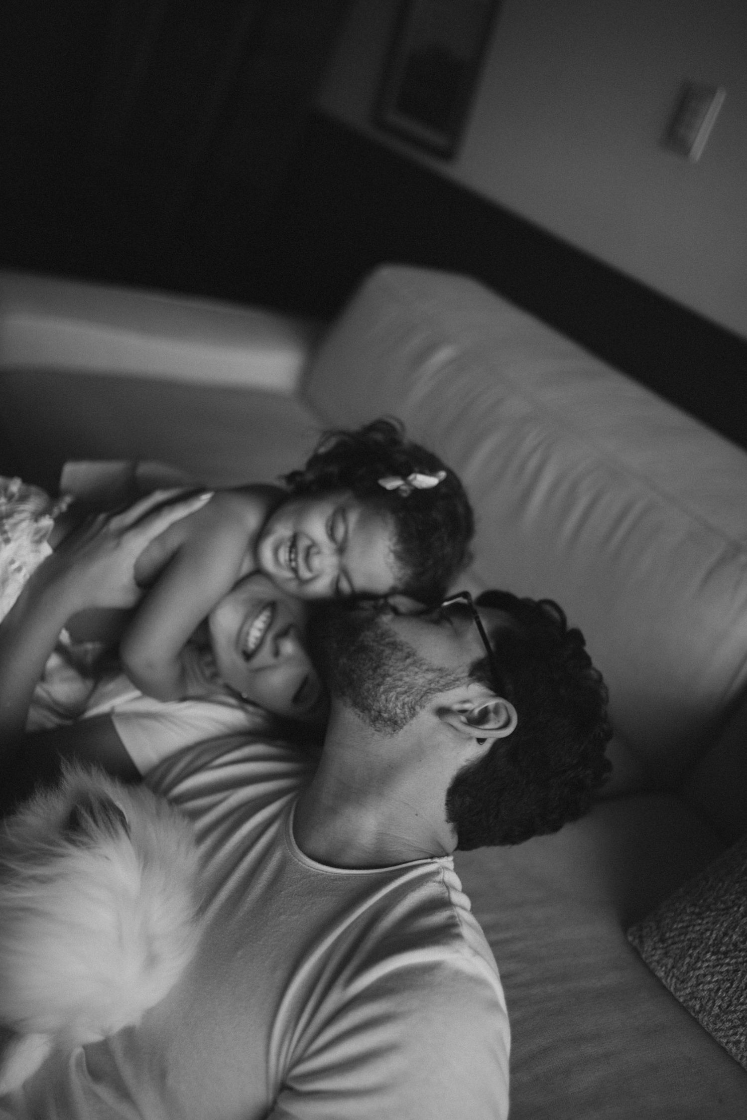 Intimate black and white portrait of family sharing joyful moment on couch.