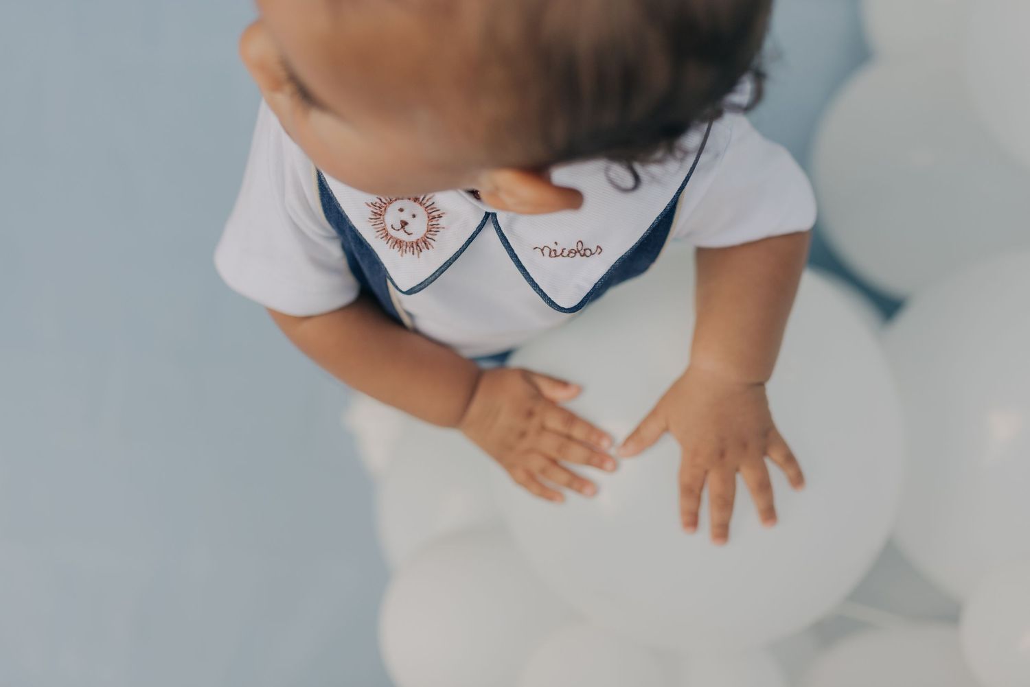 Close-up view of baby wearing white outfit with navy sailor collar detail.