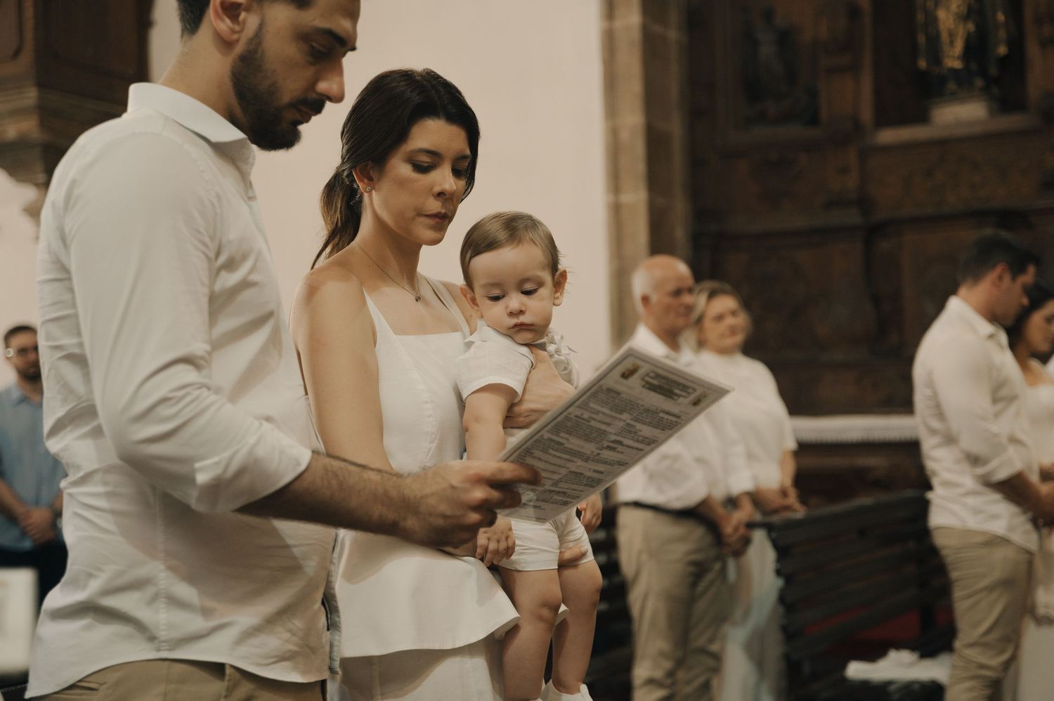 Couple in white attire sharing an intimate moment during a church ceremony.