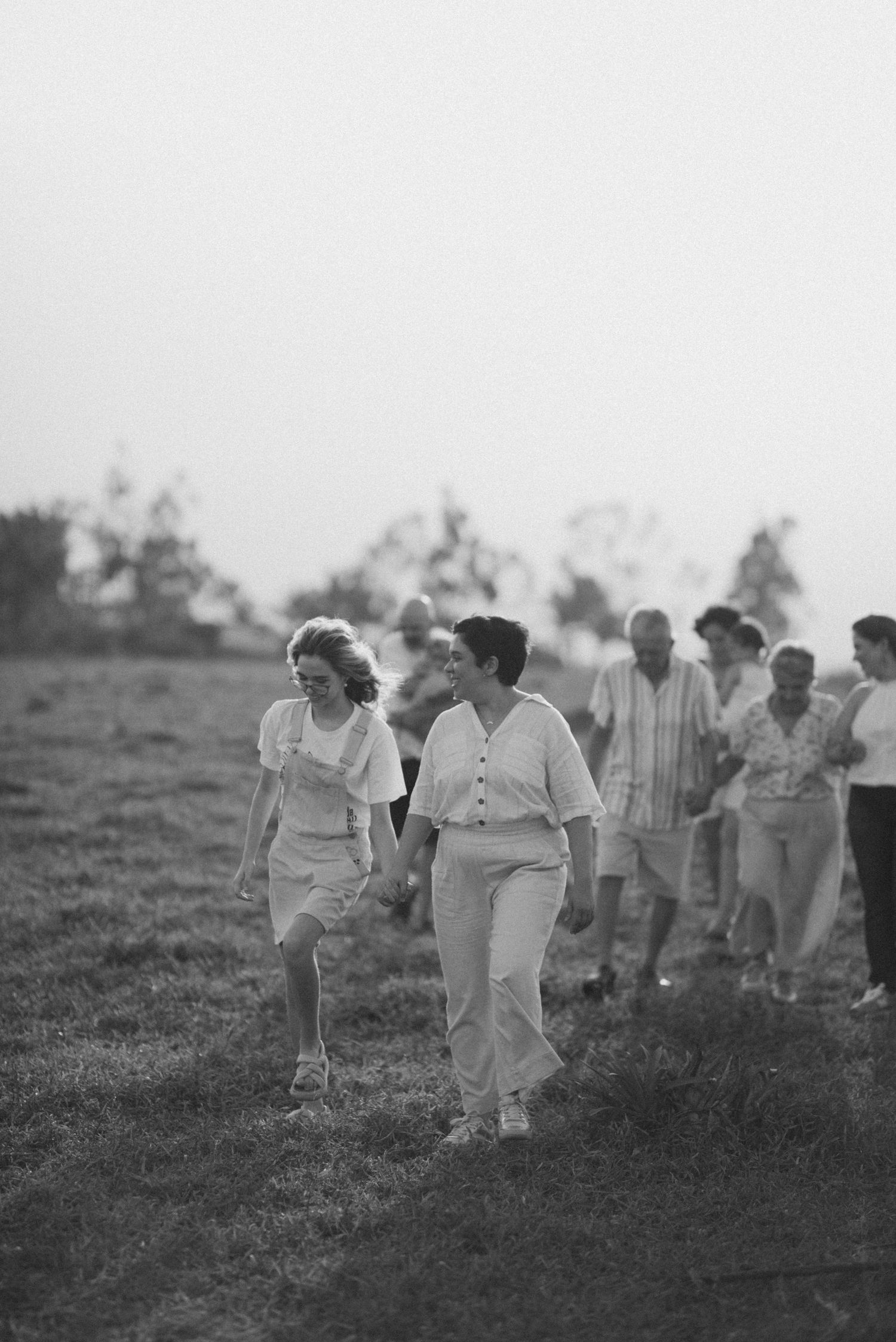 A group of people walking together across a grassy field in vintage black and white photography.