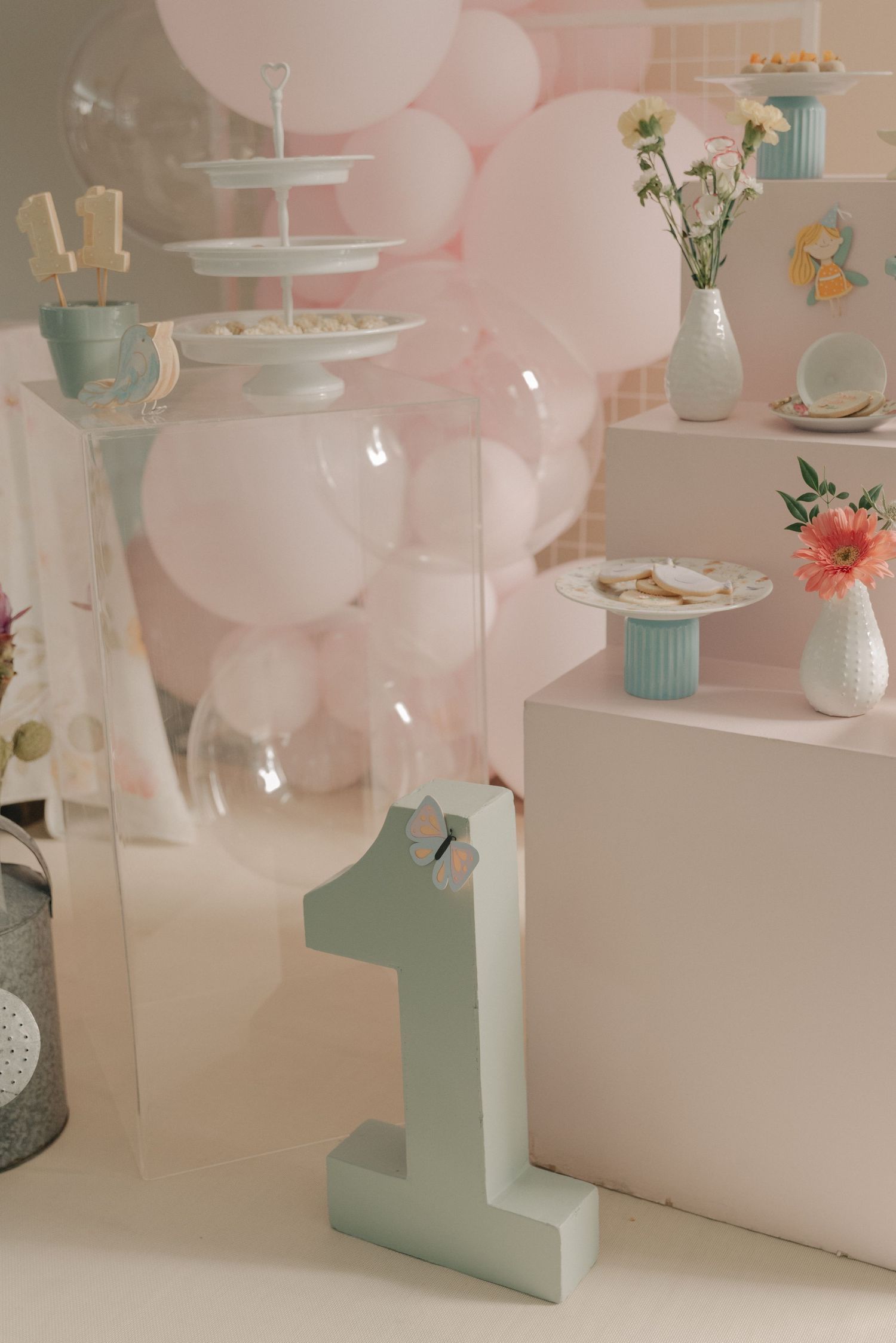 A first birthday party setup with mint and pink decorations featuring a number one centerpiece.