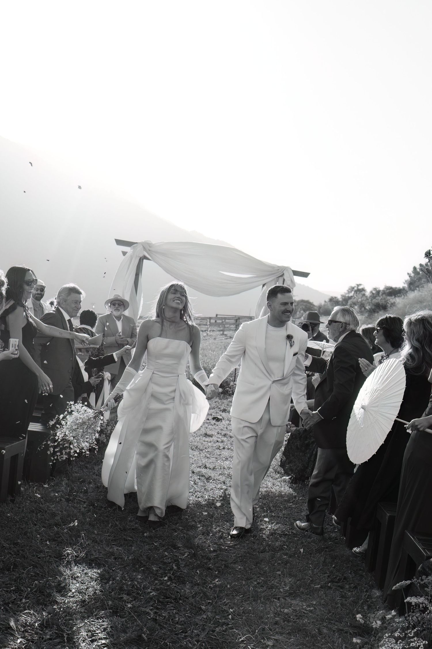 Wedding celebration on a grassy hillside with guests in throwing flower petals captured by Danielle Conner Photography in Carmel Valley, CA.