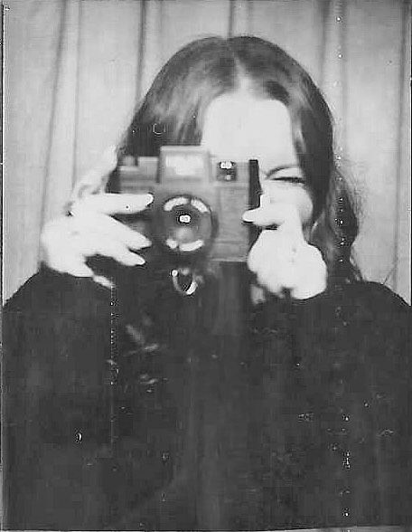 A black and white image of Danielle Conner - California wedding photographer photographing with a vintage camera covering their face.
