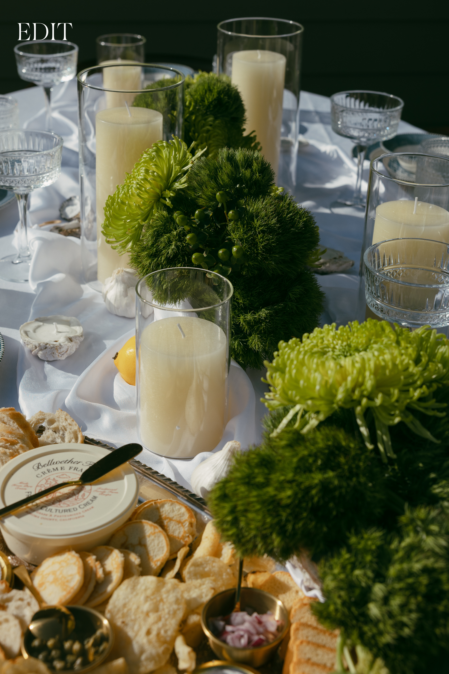 Wedding reception table detail with green moss decor, white candles, and appetizer plates.