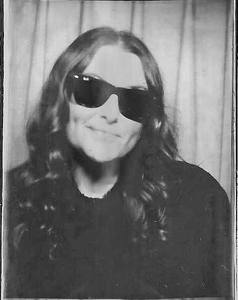 A casual black and white analog photobooth portrait of Danielle Conner - Northern Ca wedding photographer in sunglasses with long dark hair.