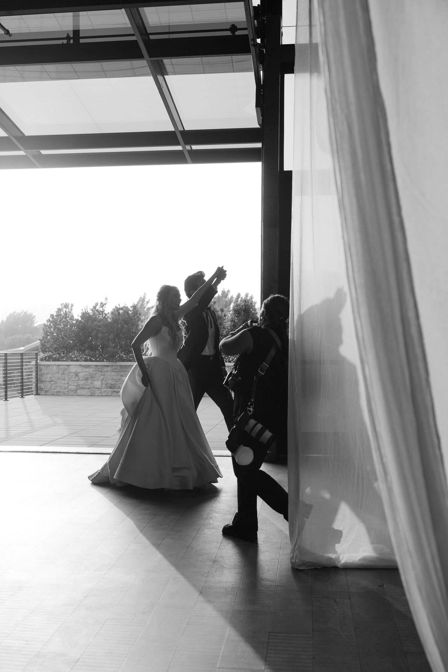 Silhouettes of people moving behind white curtains in a modern event space.