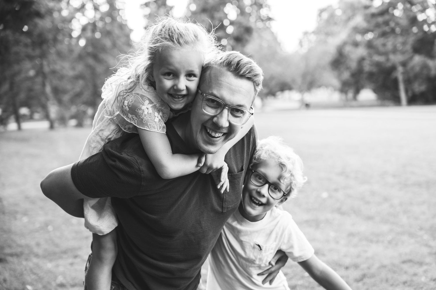 Black and white photo of a playful moment outdoors in a park with joyful expressions and laughter.