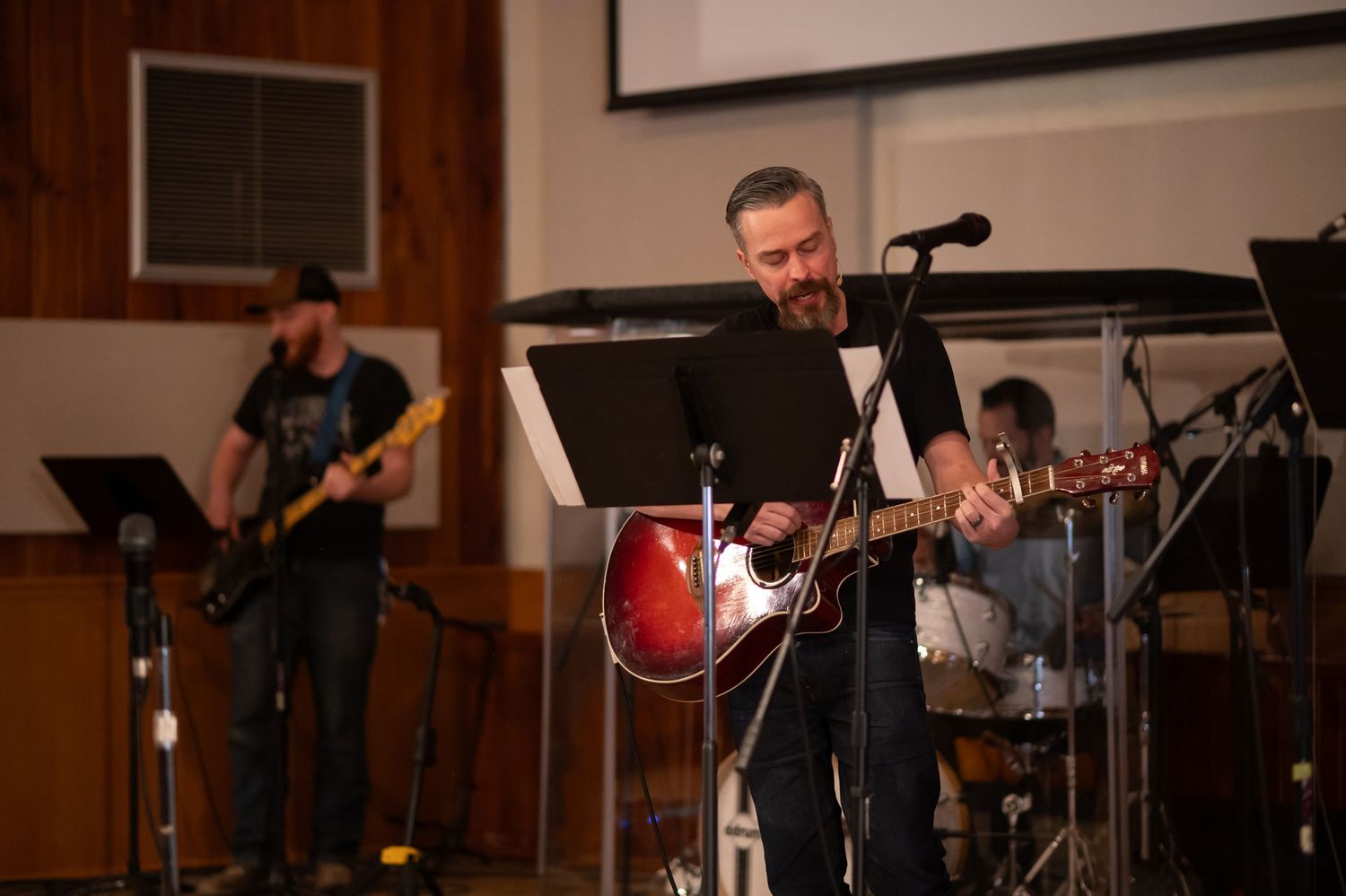 Pastor Chris plays guitar on stage with the worship team at Crossroads Morgantown during a Sunday morning church service