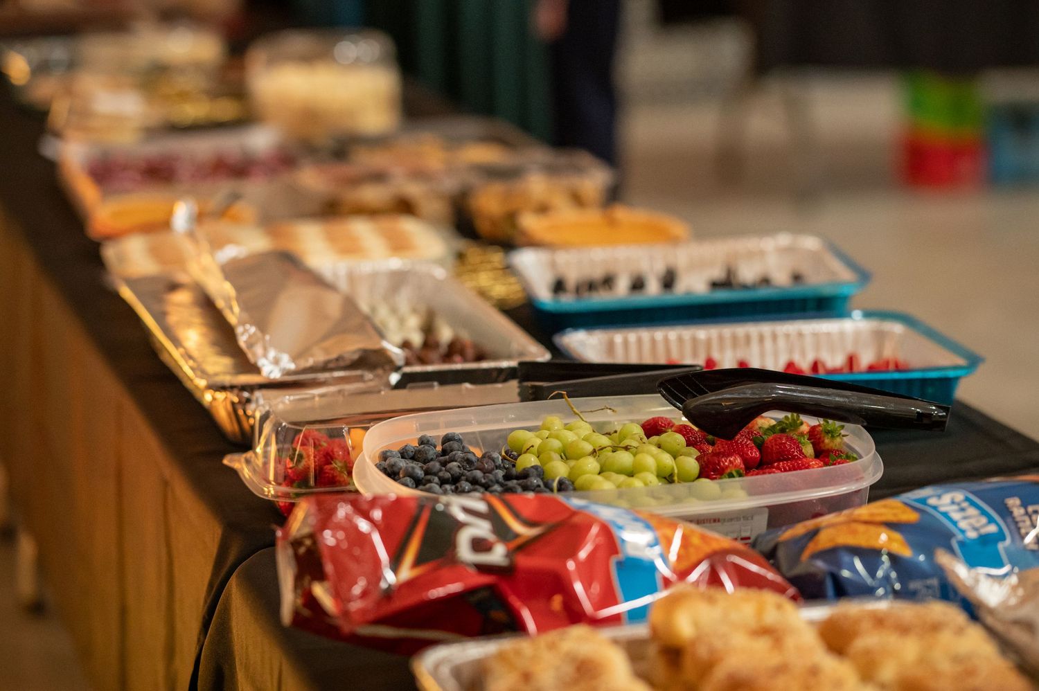 closeup of a tray of fruit on a table laden with potluck food at a Crossroads event
