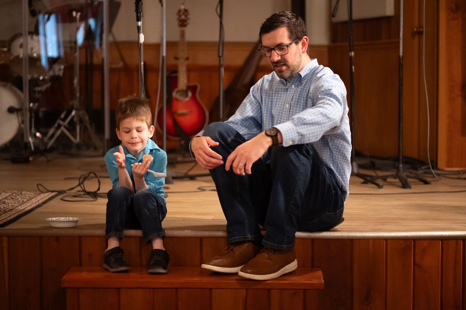 Pastor Scott sits on the stage at Crossroads Morgantown and chats with a little boy after a Sunday morning church service in Morgantown, WV