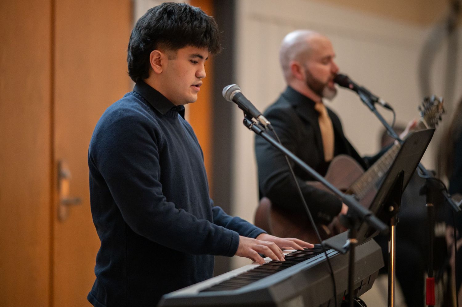 two members of the worship team play piano and guitar and sing at a Crossroads event