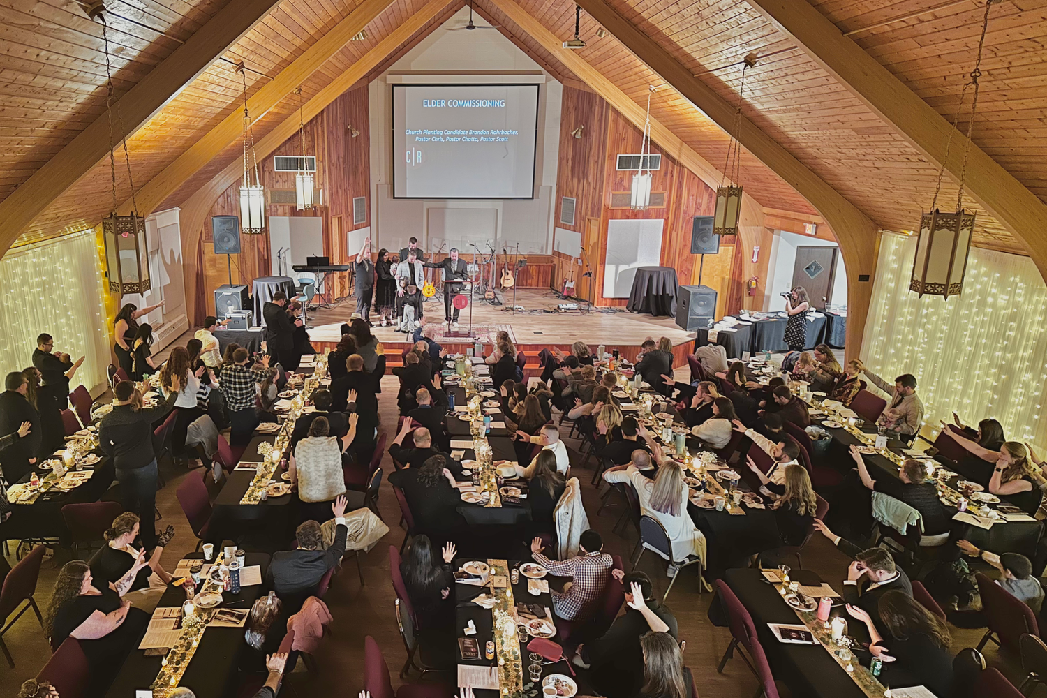overhead wide-angle view showing the auditorium of Crossroads Morgantown filled with tables and Crossroads members attending an event