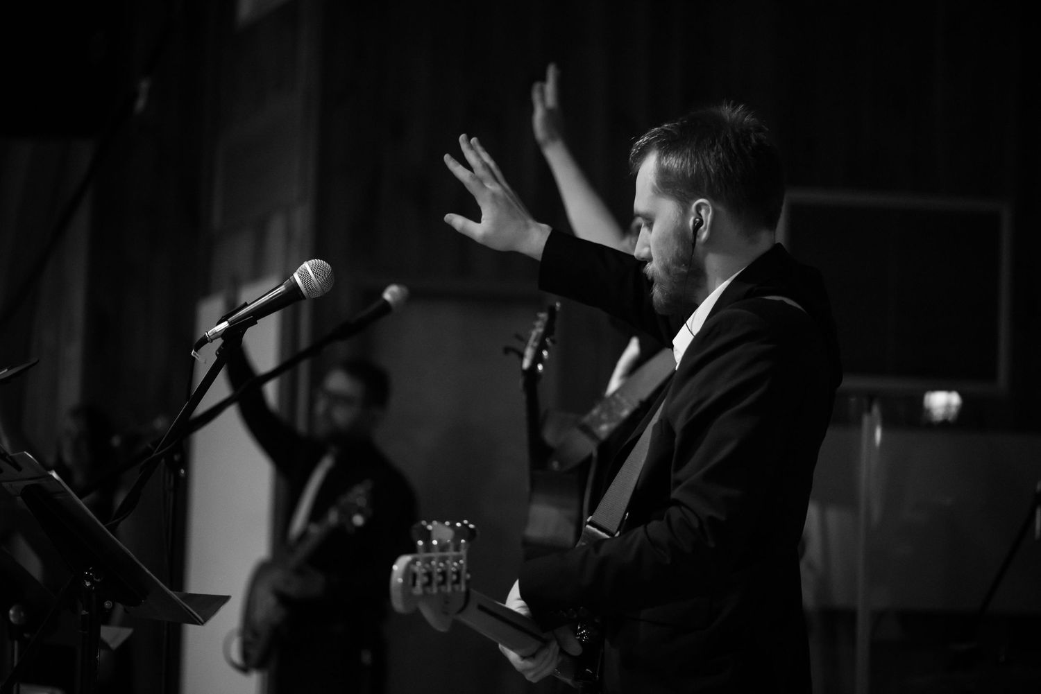 black and white image of a man with a guitar and one hand raised in worship on a stage at Crossroads Church in Morgantown, WV