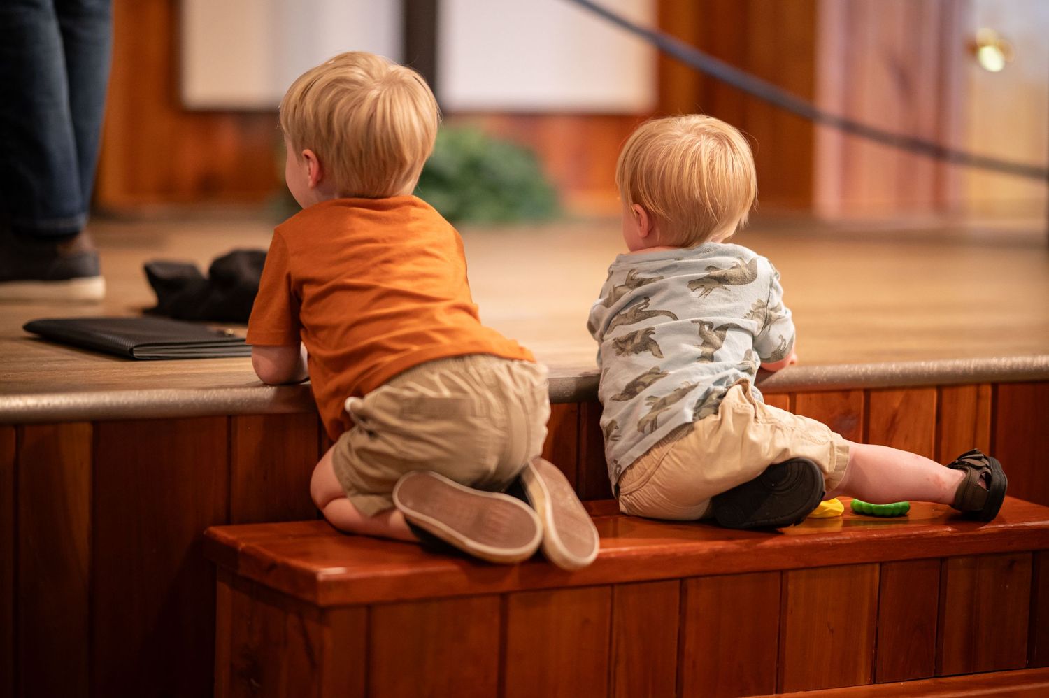 two little blond boys sit on the stairs in front of the stage at Crossroads Morgantown, watching what's happening on stage