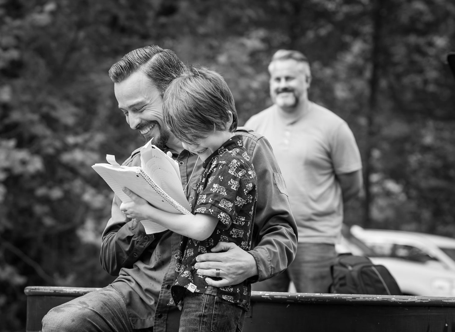 Pastor Chris laughs with his young son as he reads a prepared statement from a tattered notebook before his baptism