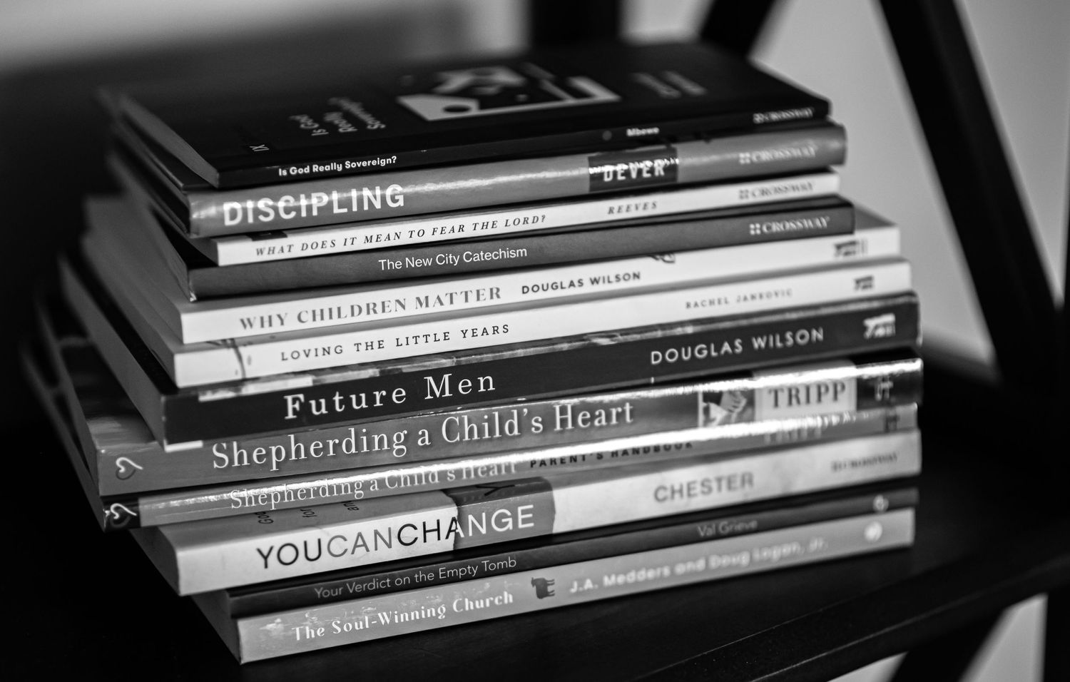Stack of Christian parenting books including Shepherding a Child's Heart and You Can Change on a chair.