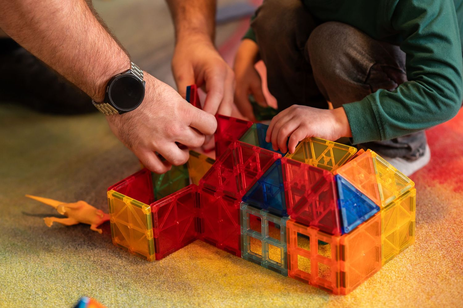 closeup of a child's hands and an adults hands working together to build a structure with magna tiles in kids' ministry at Crossroads