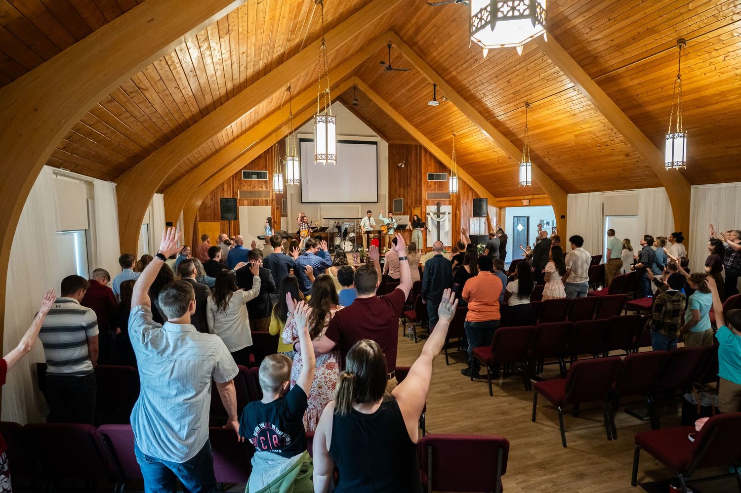 image from the back of the auditorium of Crossroads Church attendees standing and singing during Sunday worship service as musicians lead