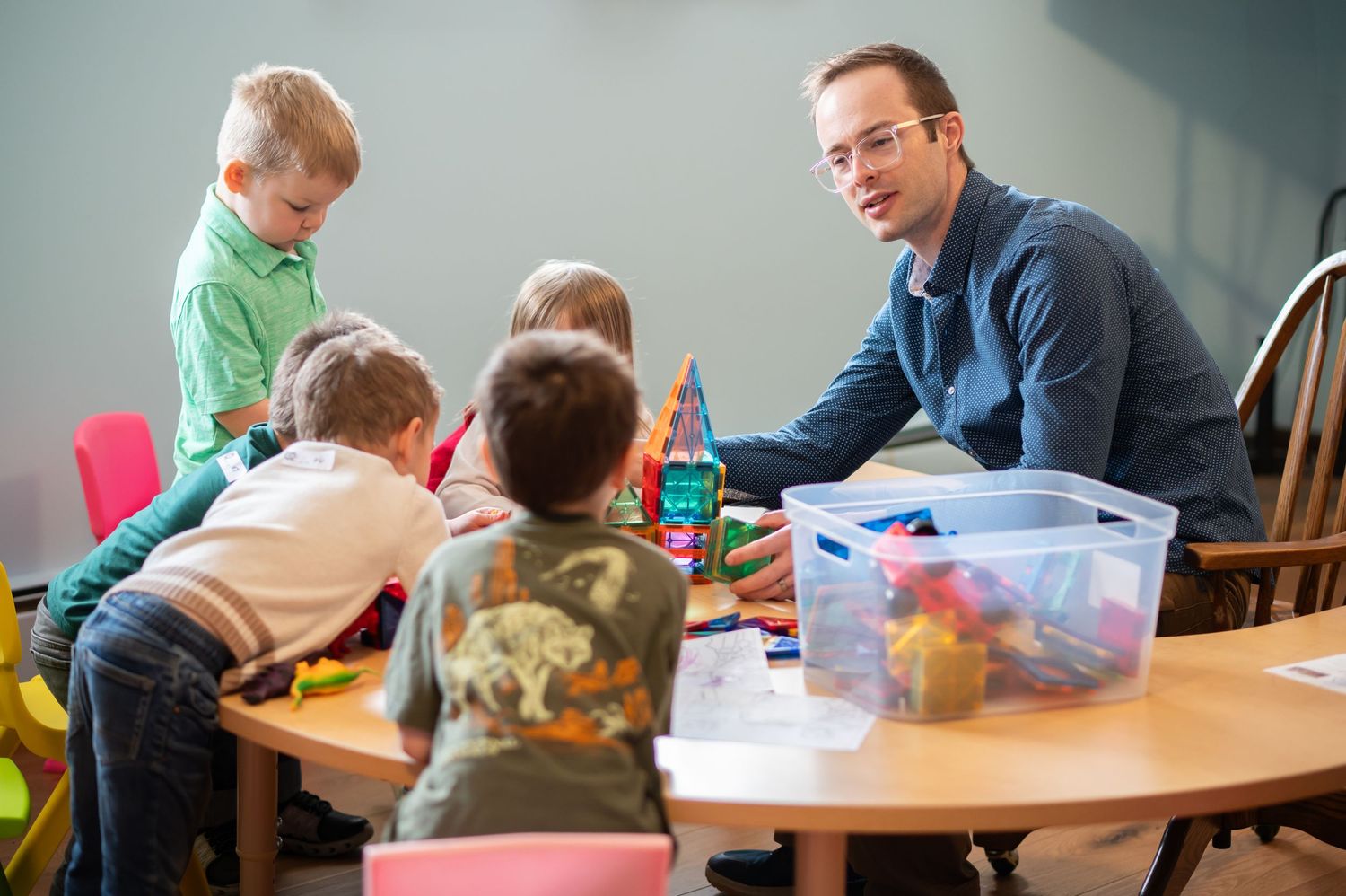 a preschool Sunday school teacher teaches a group of little children gathered around a classroom table in Crossroads' kids' ministry