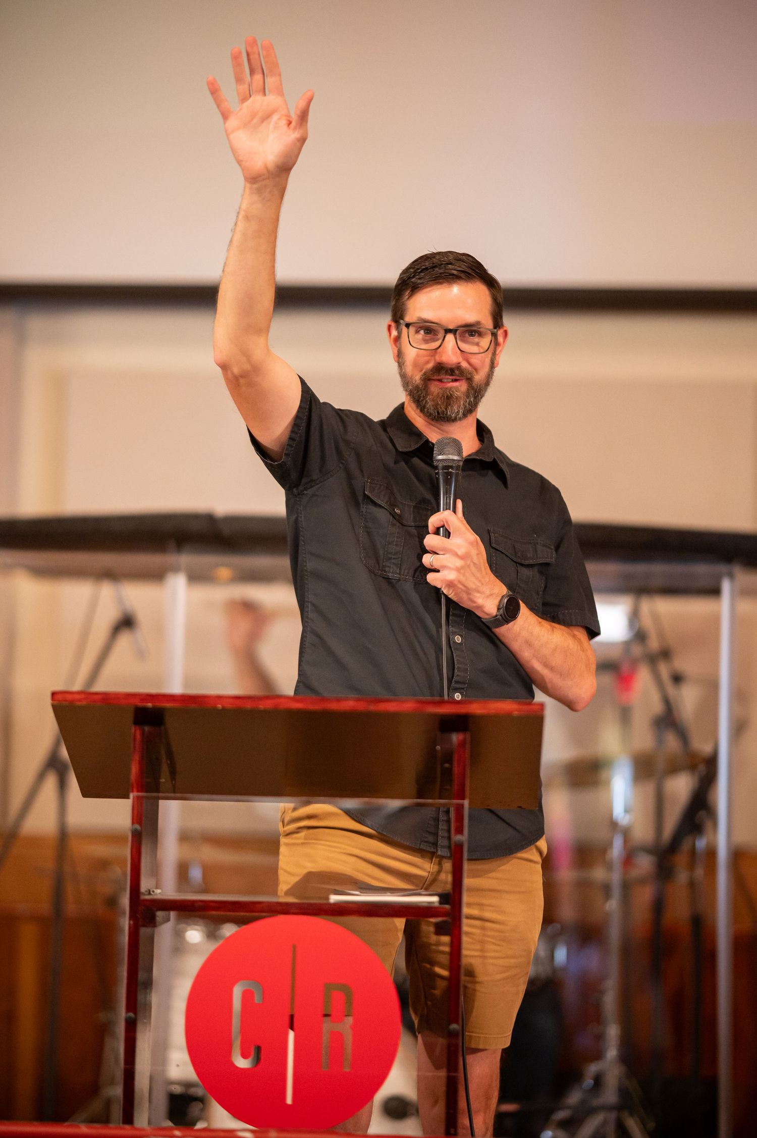 Pastor Scott preaches with a hand raised from the stage of Crossroads Morgantown during a Sunday morning church service