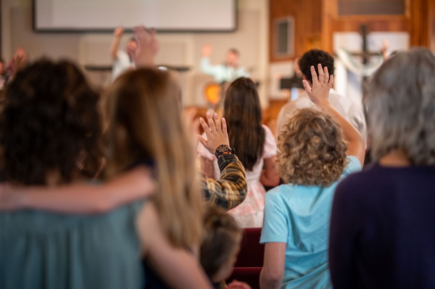 church attendees stand with hands raised during worship at a Sunday morning church service at Crossroads Morgantown
