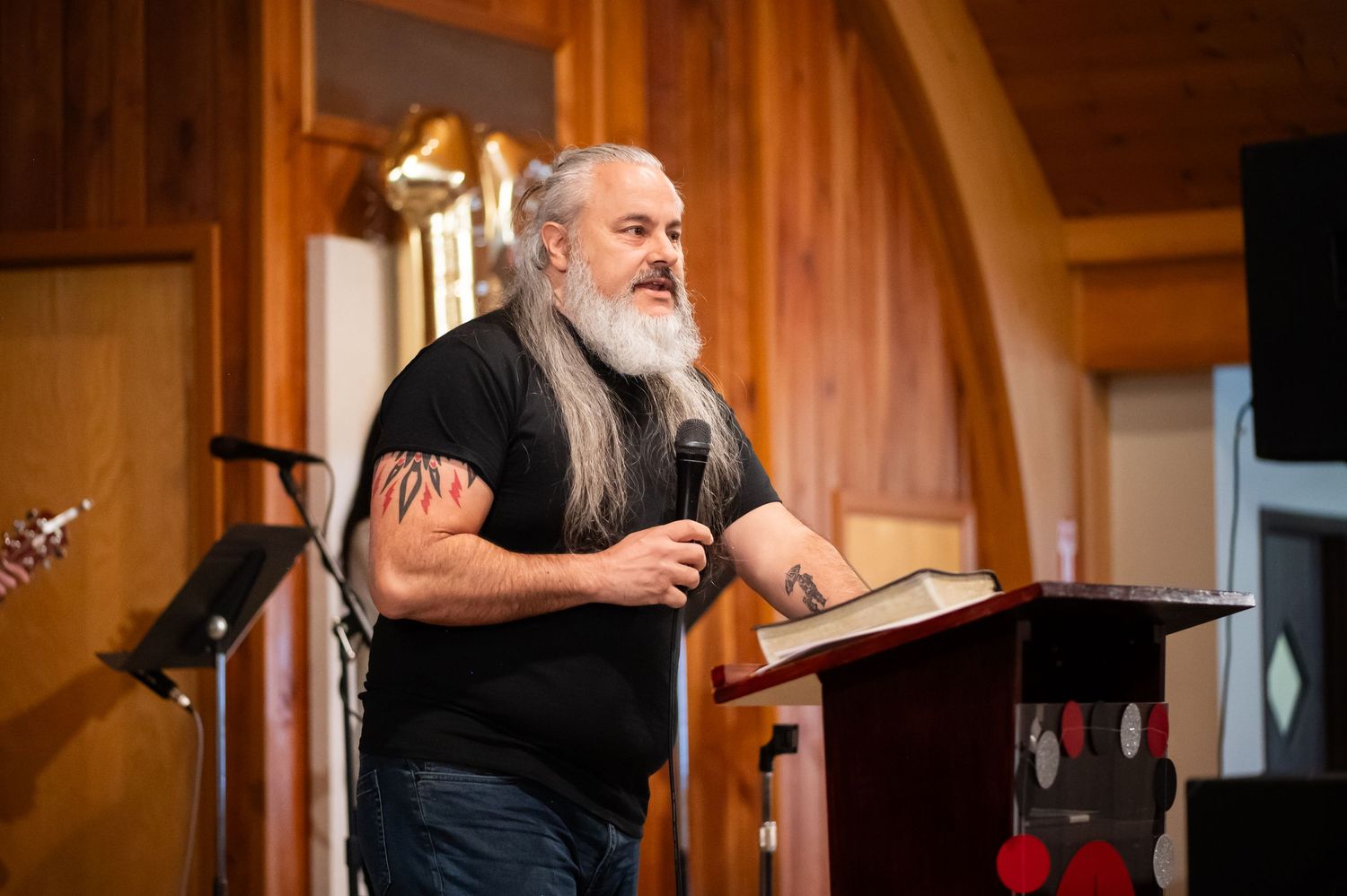 Pastor Chatto preaches at the pulpit from an open Bible on the stage at Crossroads Morgantown during a Sunday morning church service